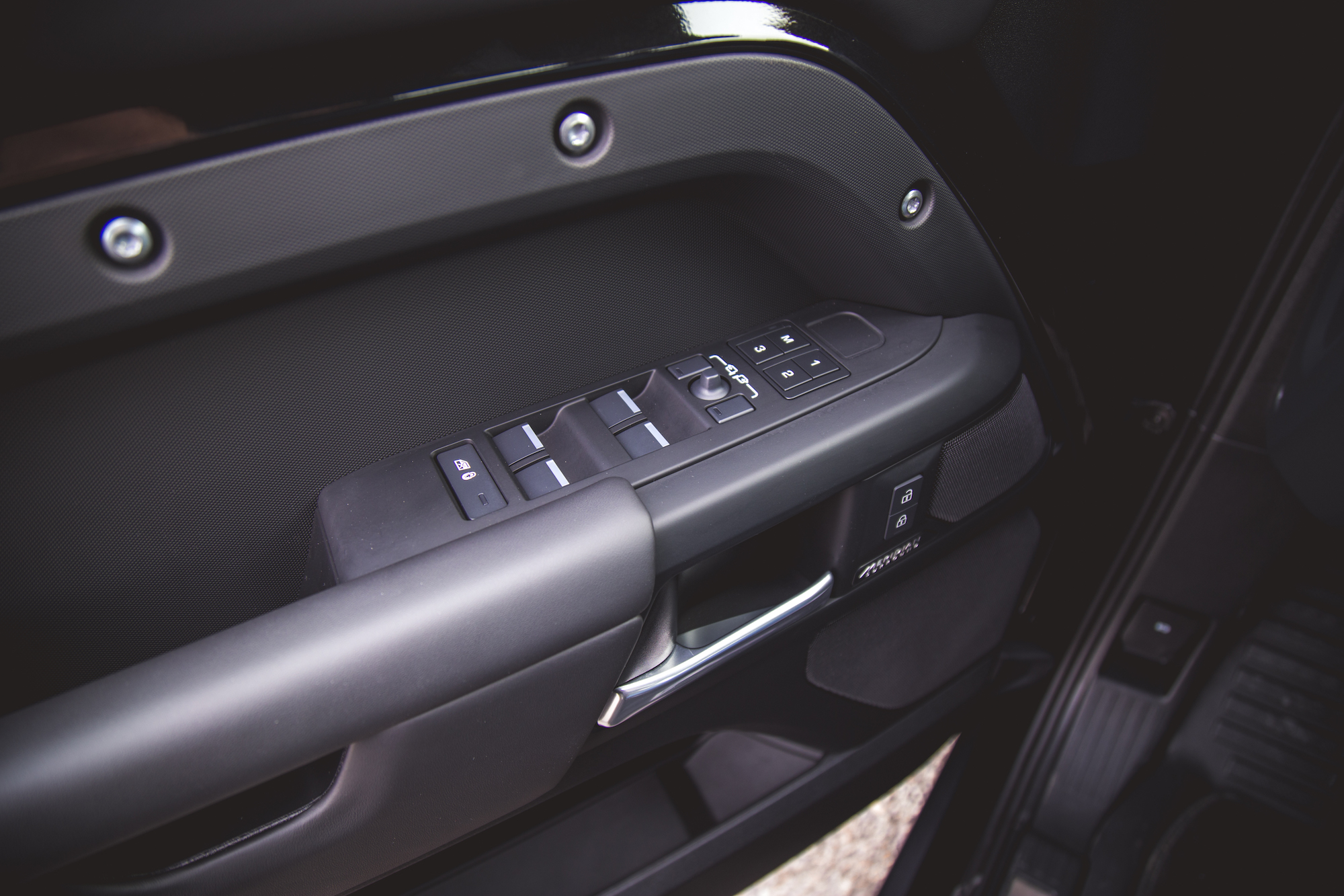 Close-up of the door control panel in a 2026 Land Rover Defender 130, featuring window switches and lock buttons.