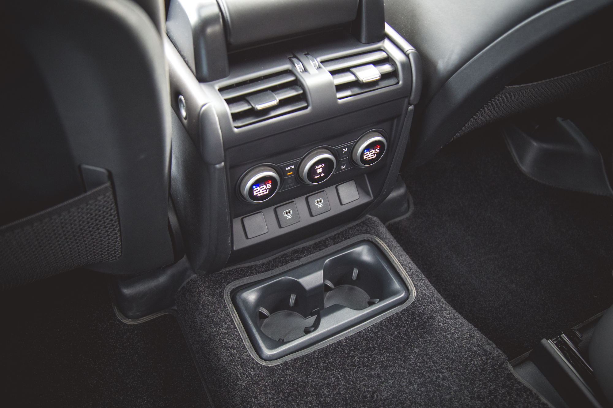 Interior view of the 2026 Land Rover Defender 130 P400 X-Dynamic SE showing climate control panel and cup holders.
