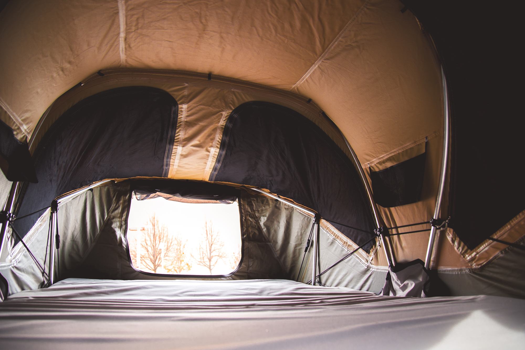 Interior view of a rooftop tent showing the sleeping area and windows.