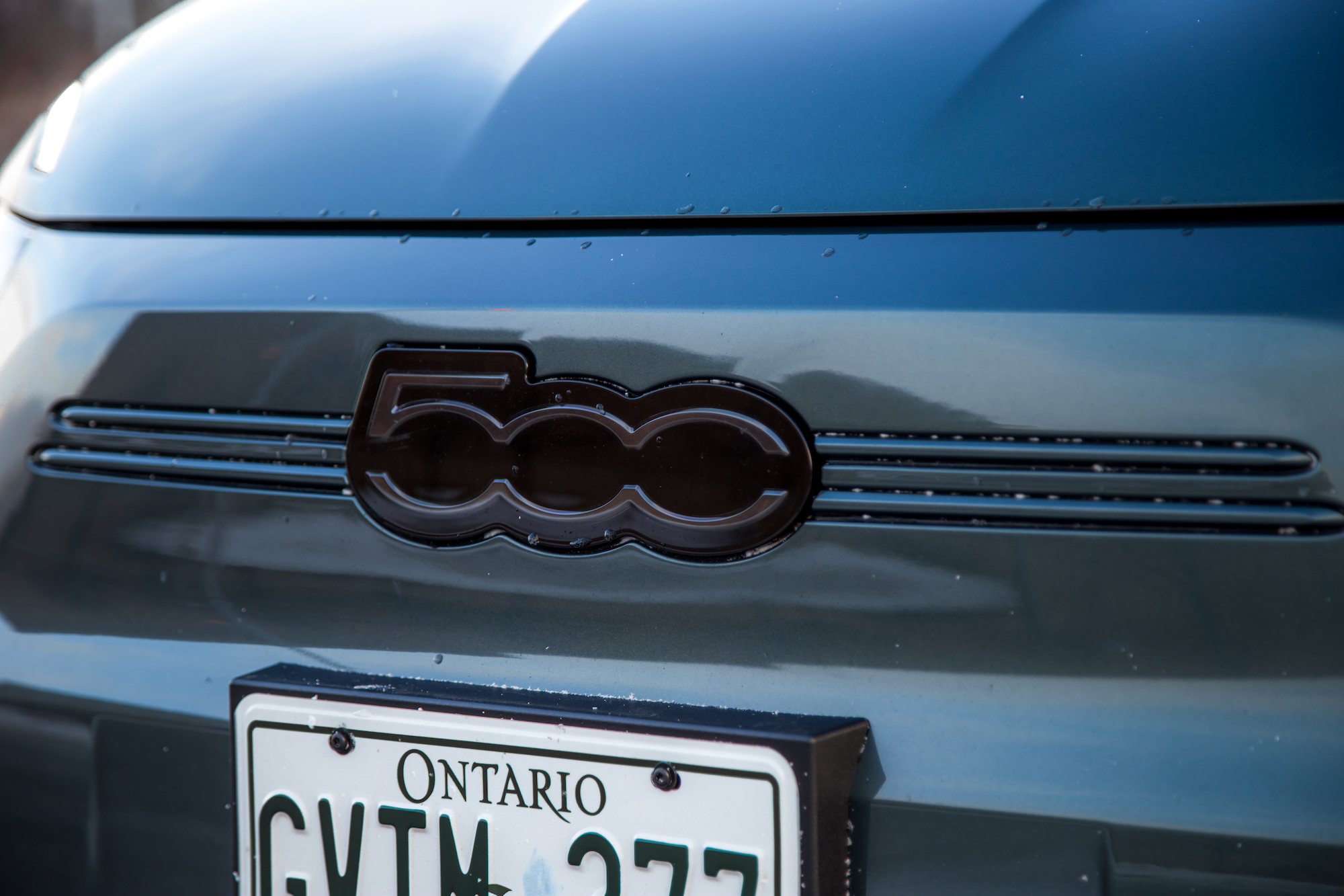 Close-up of the rear emblem of a Fiat 500, featuring the number '500' and sleek design elements, with a visible Ontario license plate below.