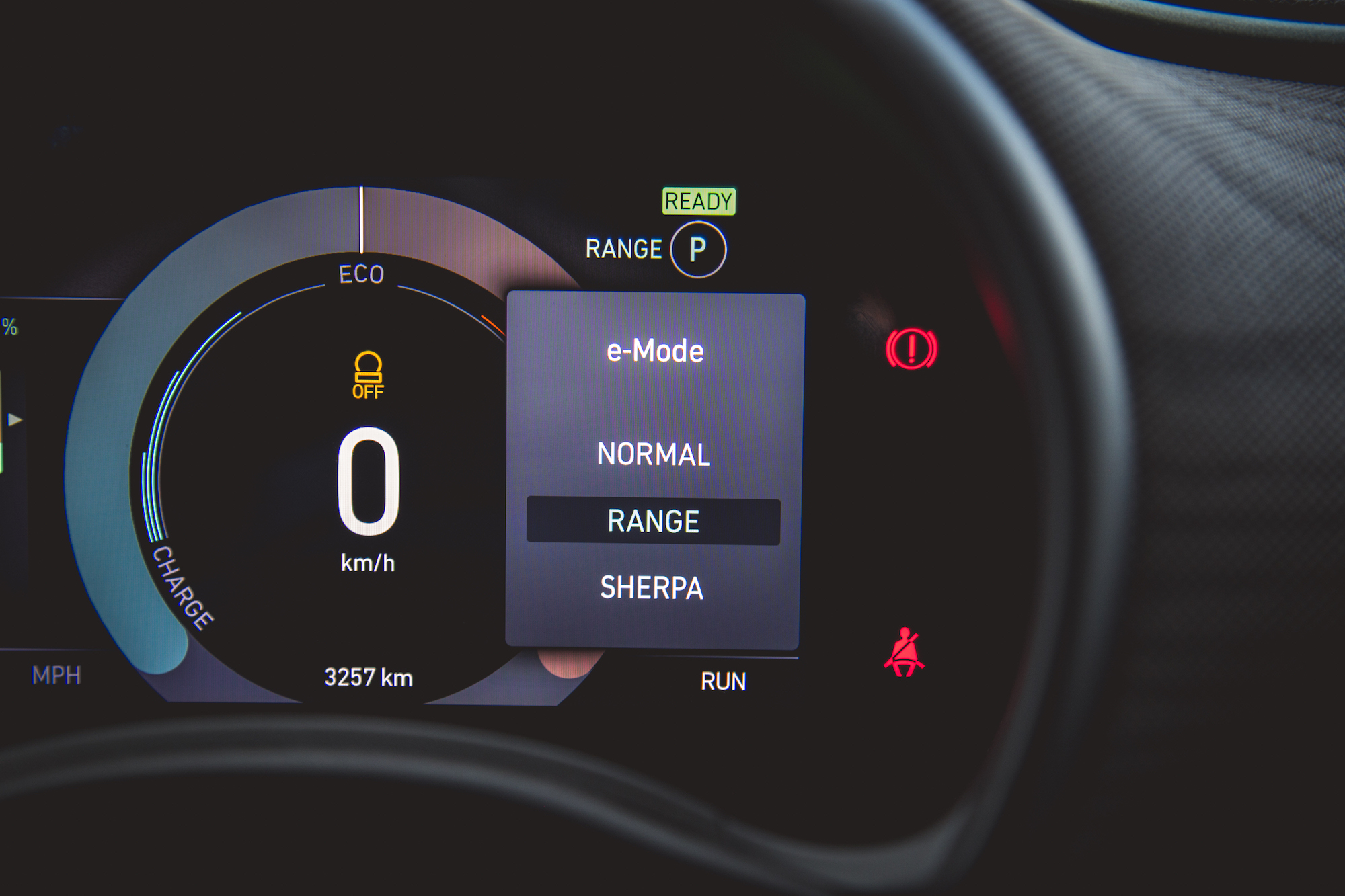 Dashboard display showing speed as 0 km/h, mode options including e-Mode, Normal, Range, and Sherpa, with indicators for range and charging status.