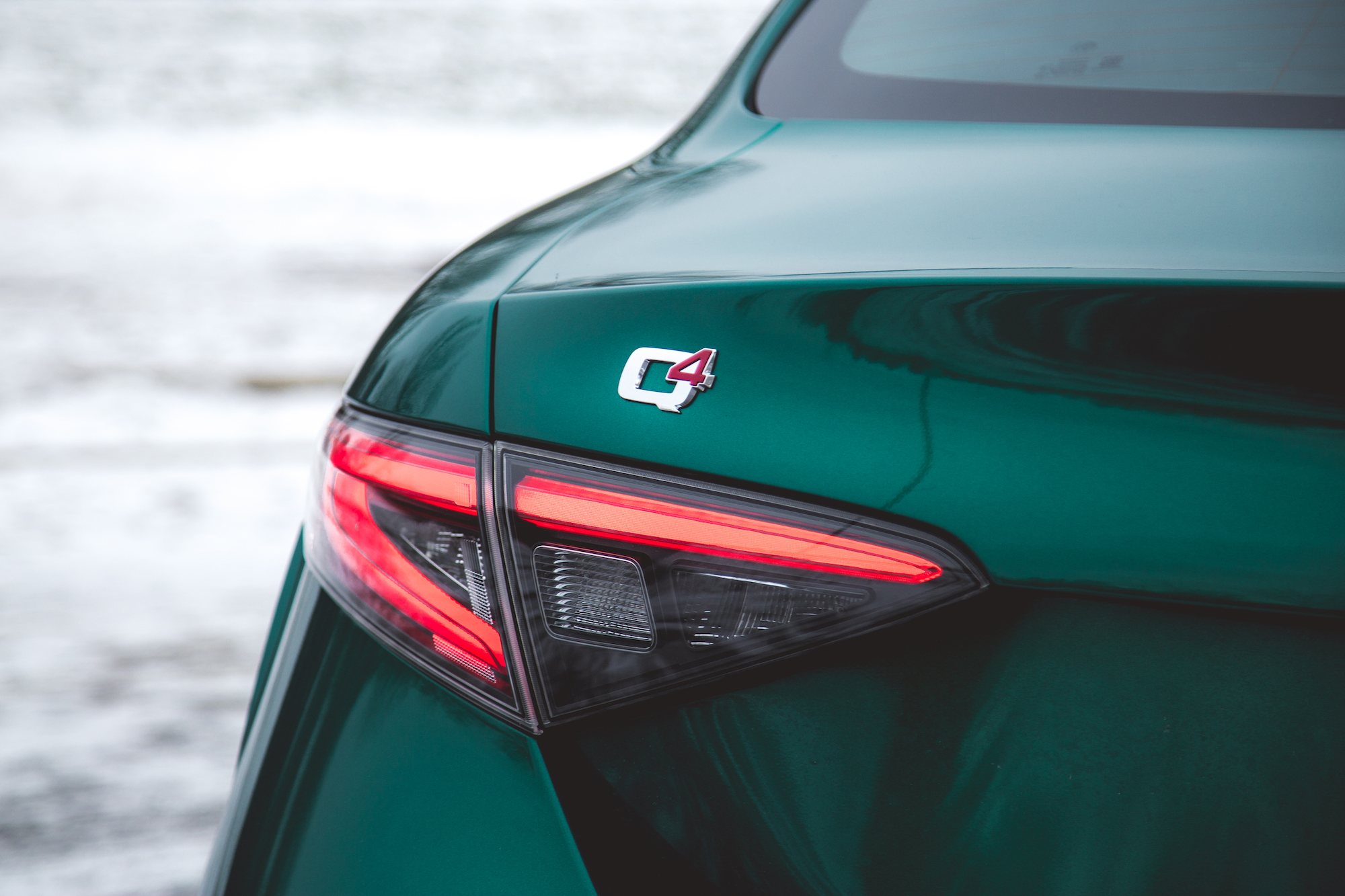 Primer plano de la parte trasera de un automóvil verde con la insignia Q4 y luces traseras.