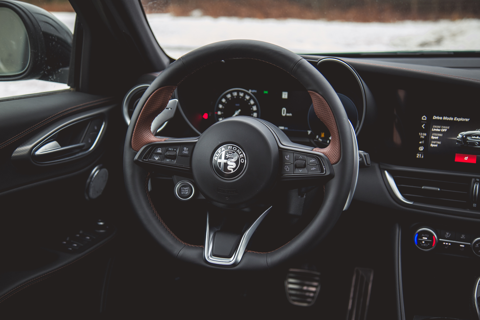 Vista en primer plano del tablero interior de un automóvil moderno, que incluye un volante forrado en cuero con controles, pantalla en el tablero y área de cambio de marchas.