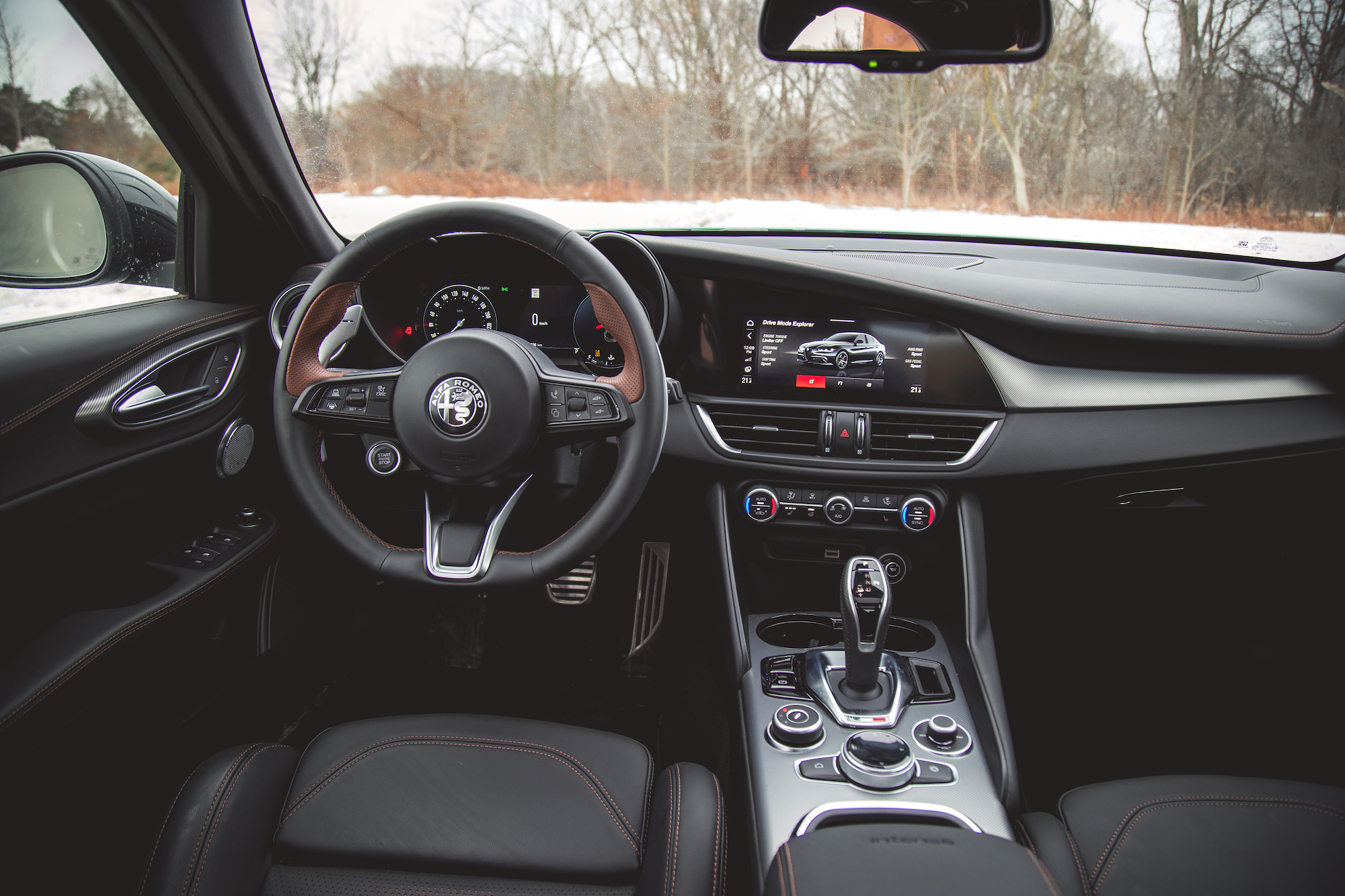 Vista interior de un automóvil moderno con volante forrado en cuero, tablero digital y panel de control con pantalla táctil.