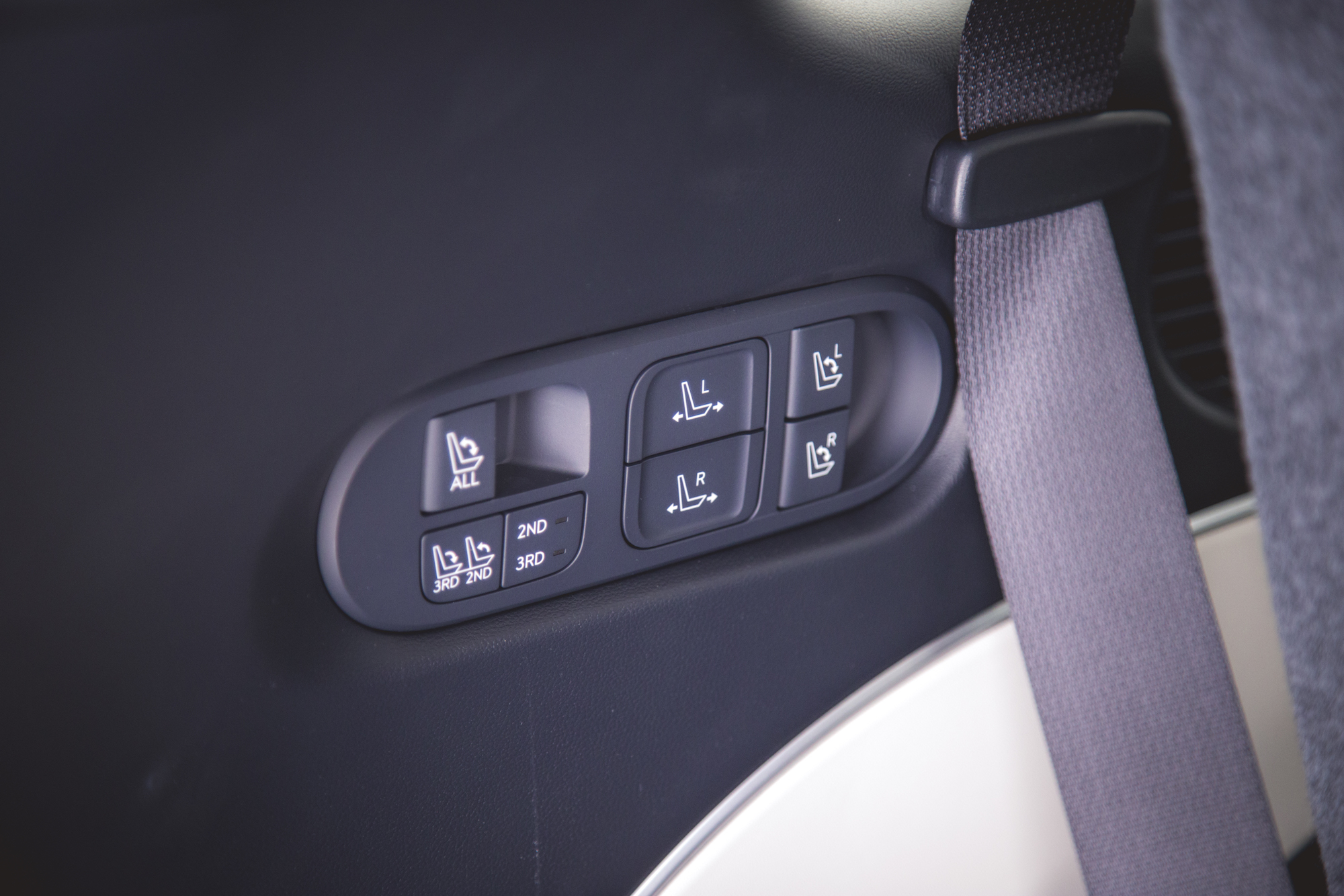 Vista interior de la puerta de un automóvil con botones de ajuste de los asientos, incluidas opciones para las posiciones izquierda, derecha y varias posiciones etiquetadas como 