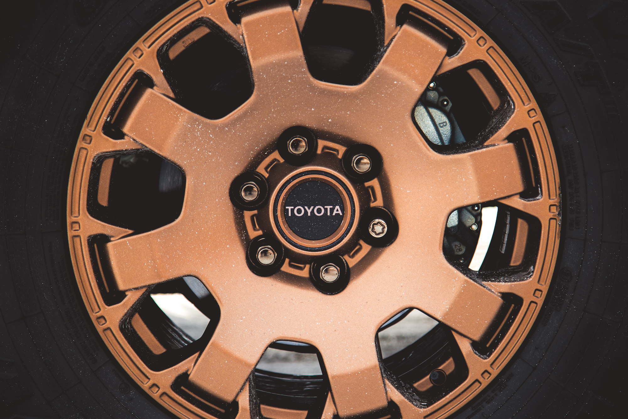 Primer plano de una llanta de aleación Toyota de color bronce con un neumático negro, que muestra el diseño y el logotipo de la rueda.