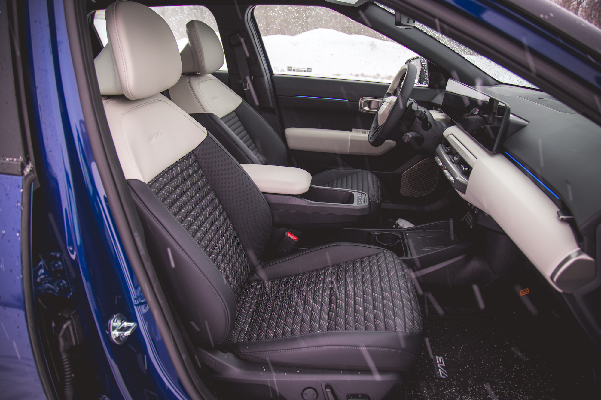 Vista interior de un automóvil moderno que muestra elegantes asientos en blanco y negro, un elegante tablero con pantalla digital y un diseño minimalista.