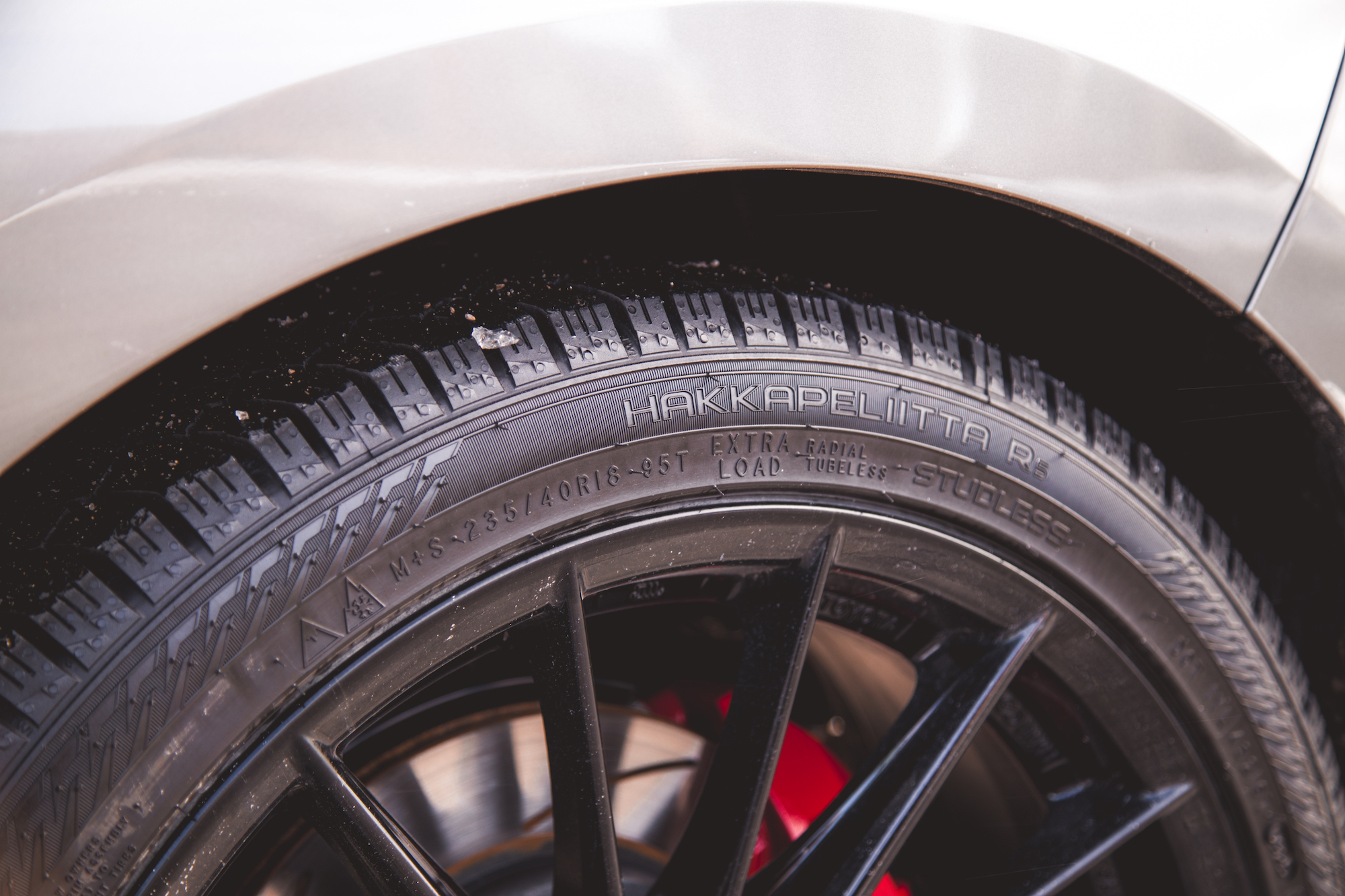 Primer plano de un neumático montado sobre una llanta de aleación negra, que muestra la banda de rodadura y la marca 'Hakkapeliitta R.'