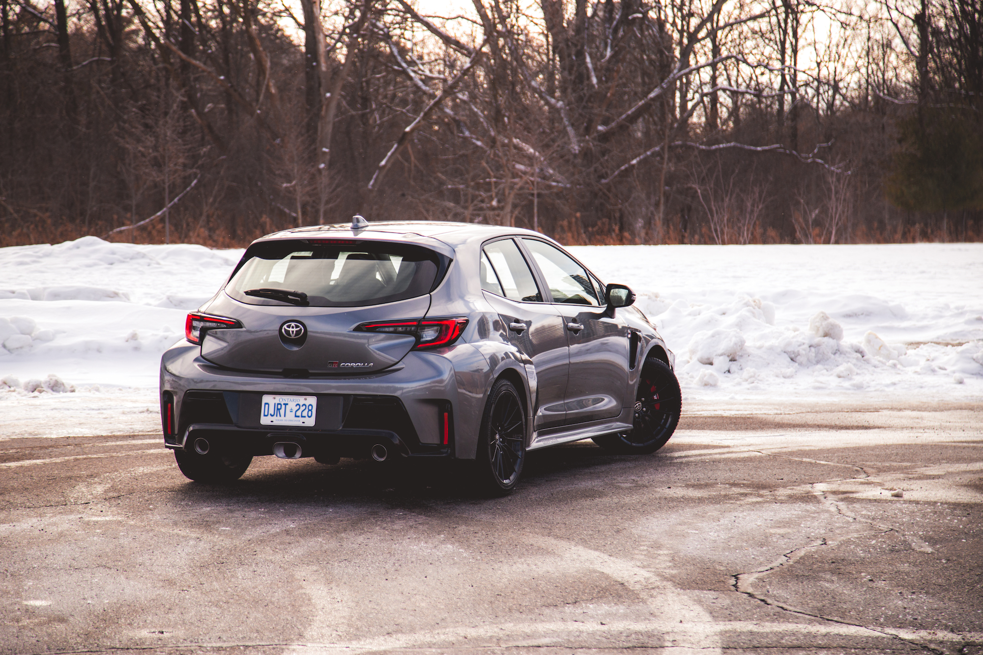 Un Toyota Corolla gris estacionado en un paisaje nevado con árboles desnudos al fondo.