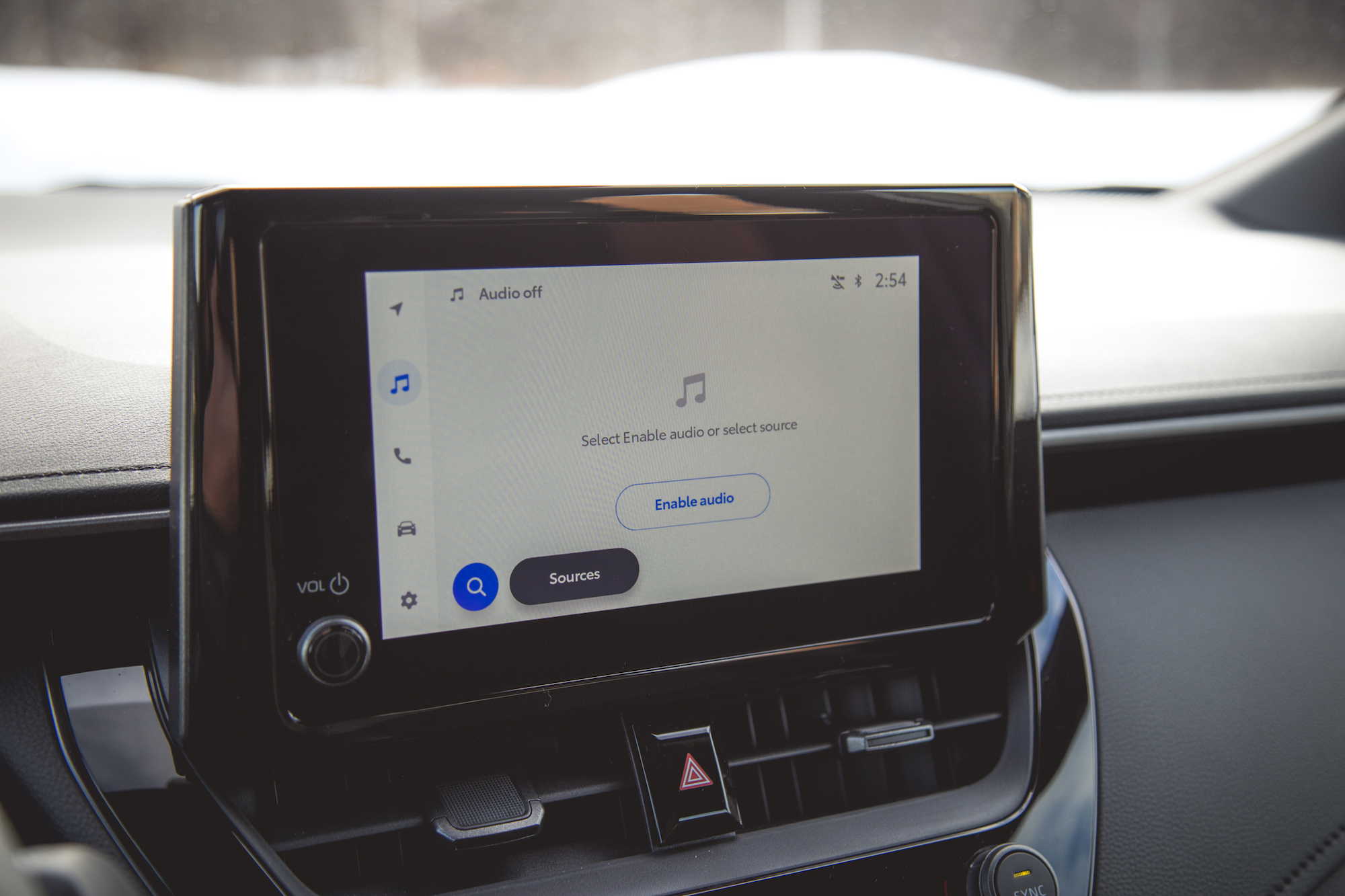 Primer plano de la pantalla del tablero de un automóvil que muestra la configuración de audio, con opciones para habilitar el audio y seleccionar fuentes.
