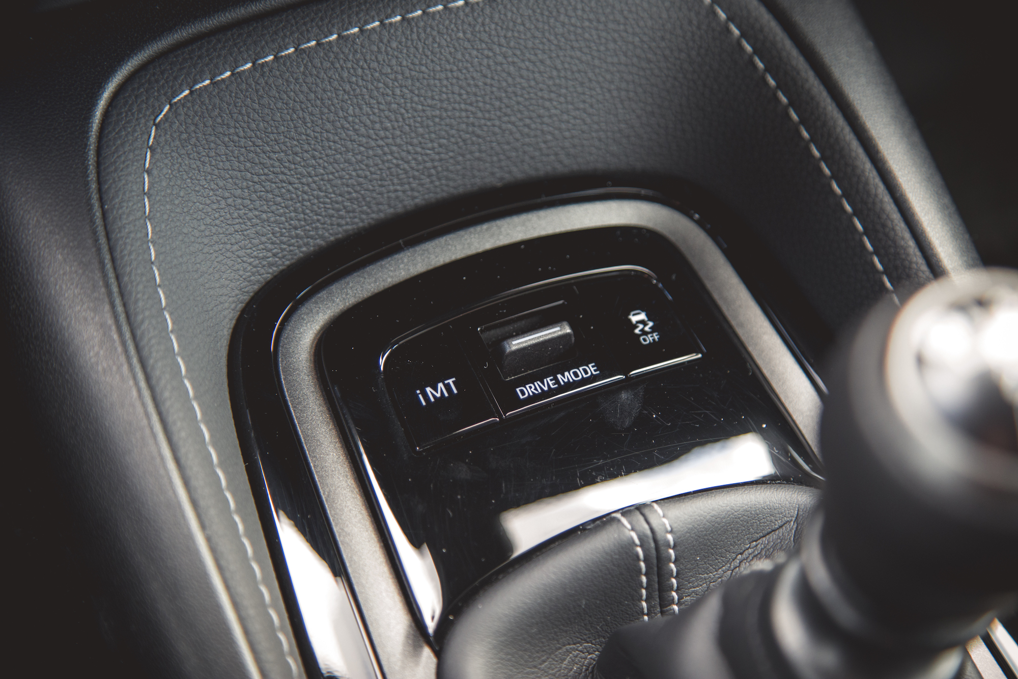 Primer plano de la consola de cambio de marchas de un automóvil con botones para iMT, modo de conducción e indicación 2WD.
