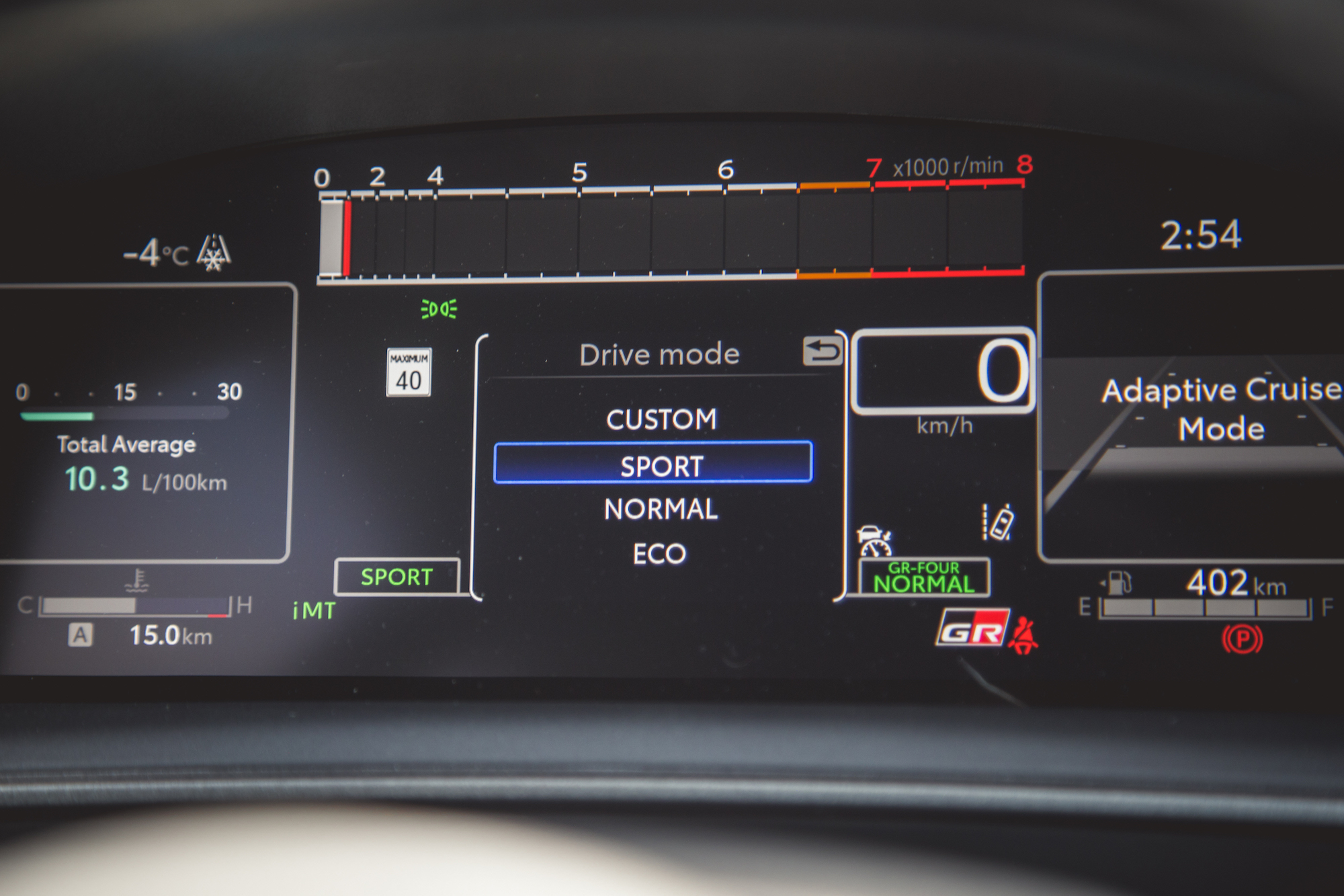 Una vista en primer plano de la pantalla del tablero digital de un vehículo que muestra los modos de conducción (Personalizado, Deportivo, Normal, Eco), la temperatura exterior (-4°C), el consumo promedio total de combustible (10,3 L/100 km) y la autonomía (402 km).