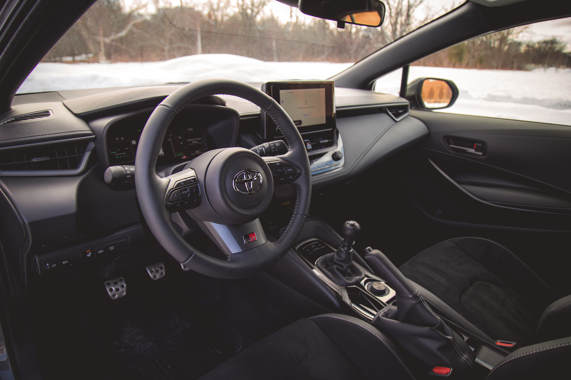 Vista interior de un automóvil Toyota que muestra el volante, la palanca de cambios y el tablero con pantalla táctil.