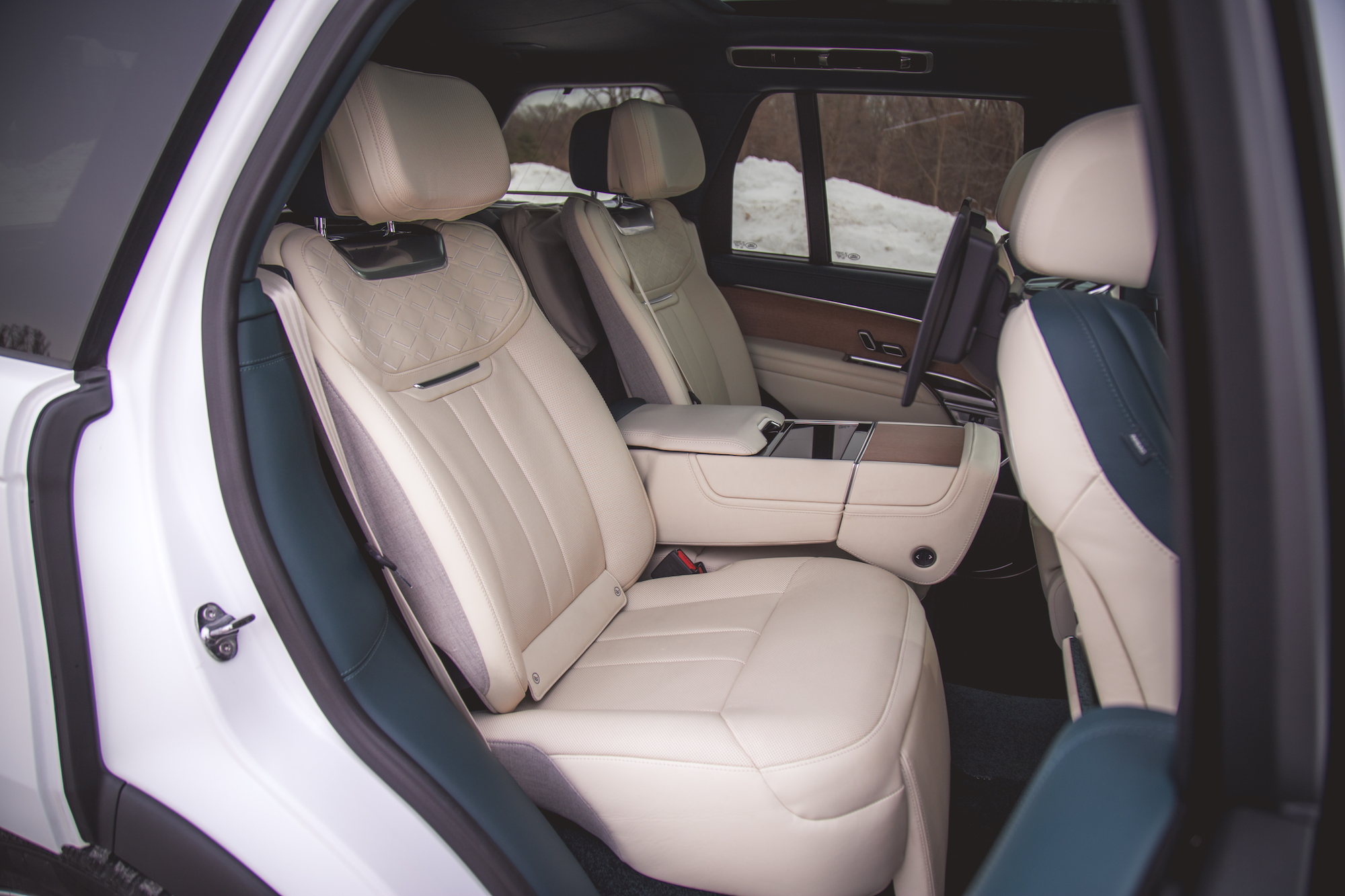 Vista interior de un vehículo de lujo que muestra dos asientos de cuero beige con una consola en el medio, destacando el diseño moderno y la comodidad.