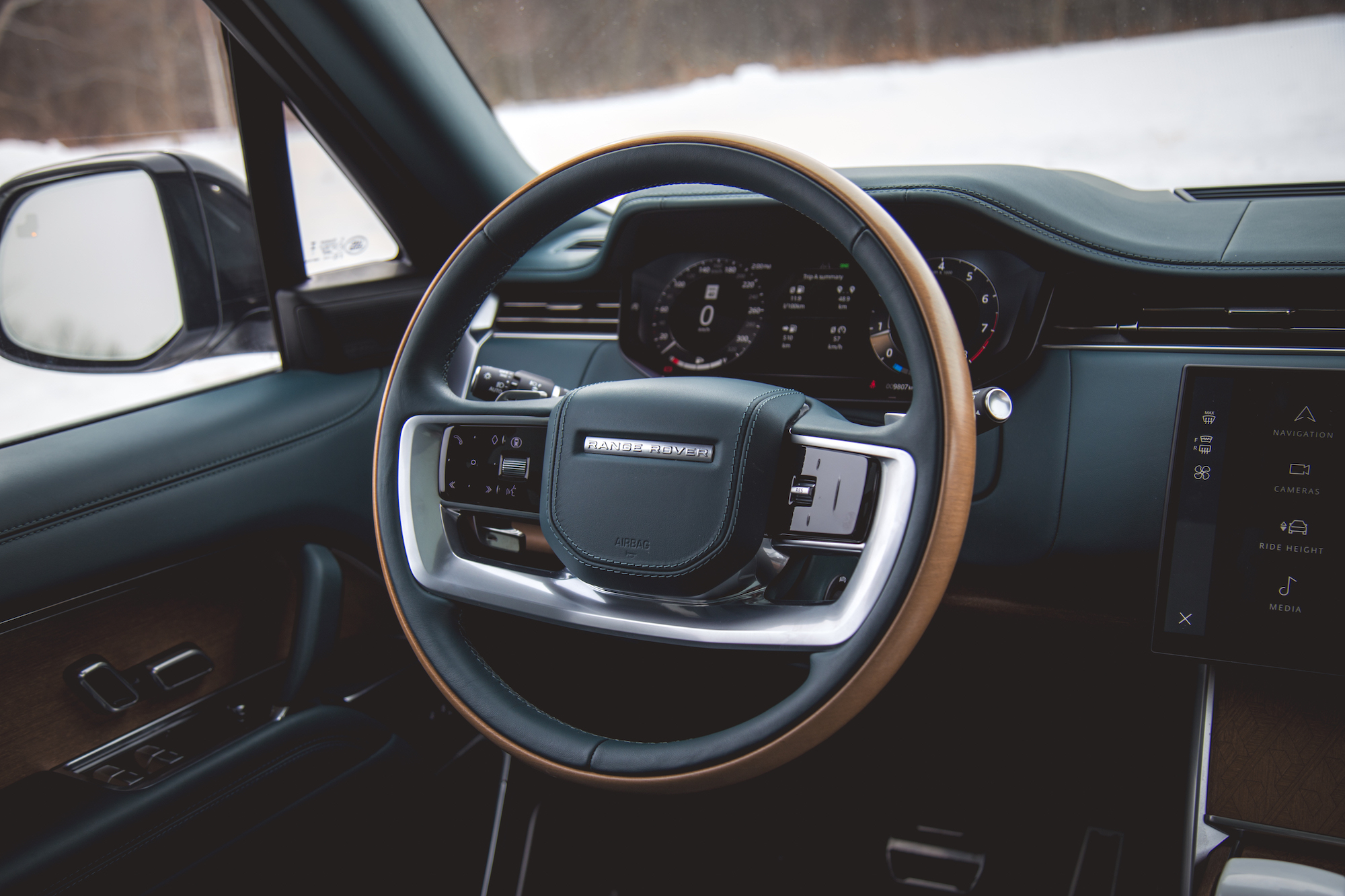 Vista interior de un vehículo de lujo que muestra un volante moderno, un tablero con pantalla digital y un panel de control.