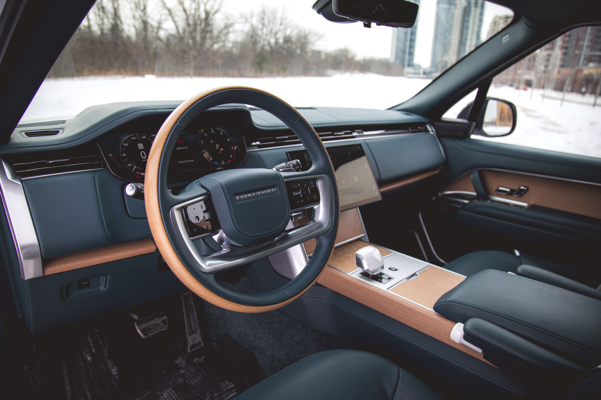 Vista interior de un automóvil de lujo que muestra un tablero moderno, un volante con detalles en madera y una pantalla táctil.