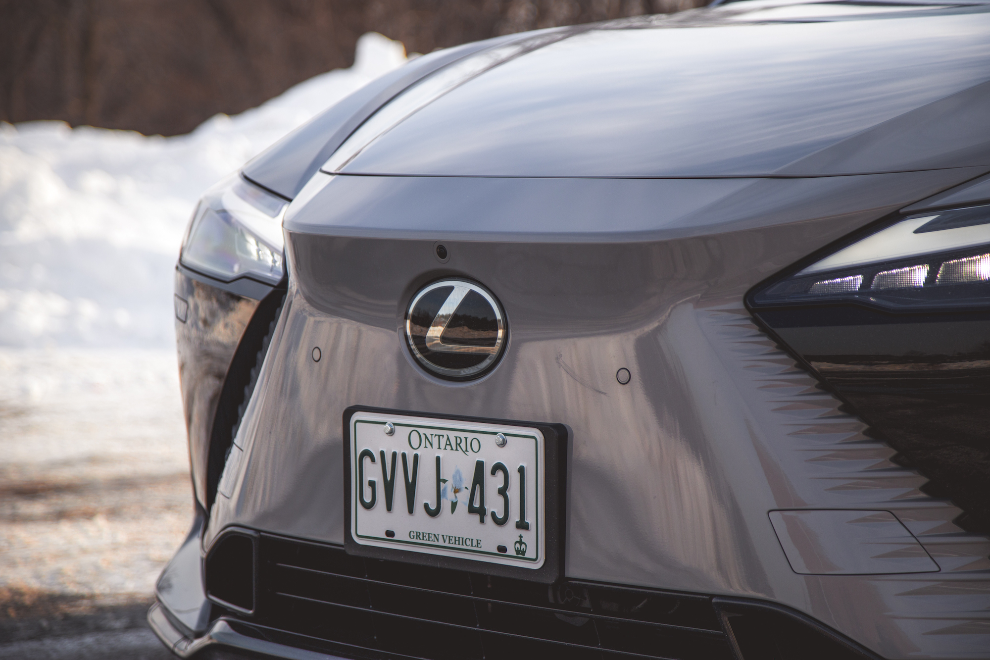 Close-up view of a Lexus car front with a visible license plate from Ontario, showing the vehicle's details against a snowy background.