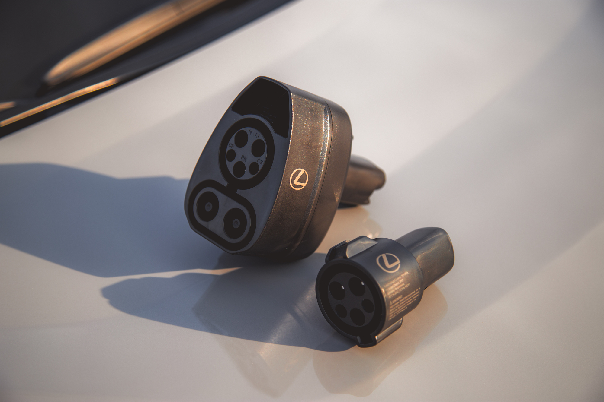 Two electric vehicle charging connectors resting on a light-colored surface, featuring a distinctive logo.