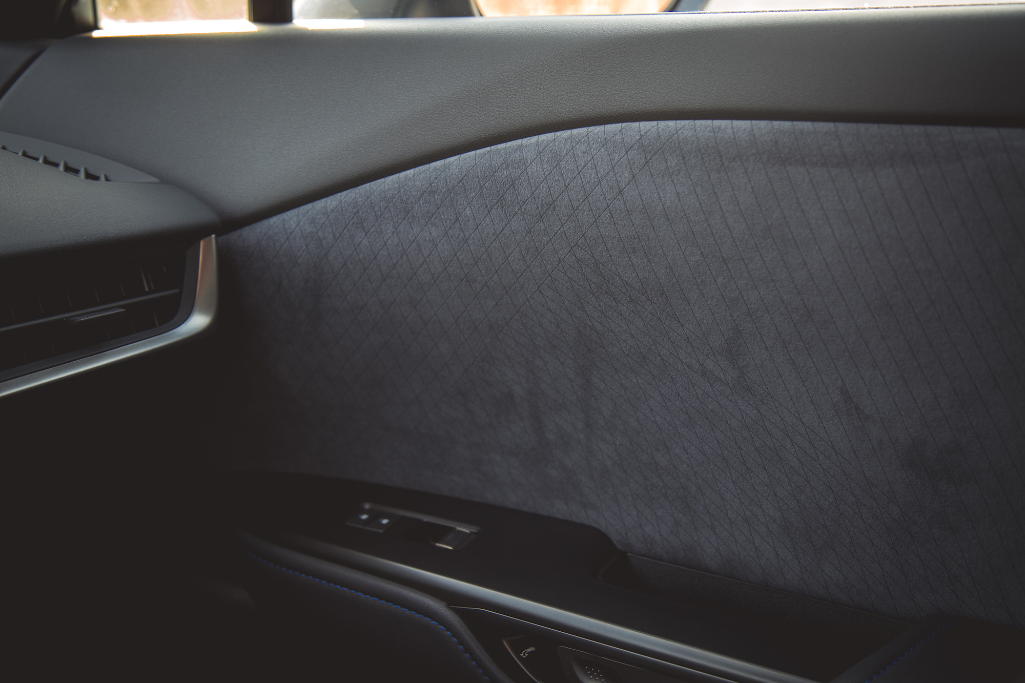 Interior view of a car door panel featuring a textured dark fabric finish and sleek metallic accents.