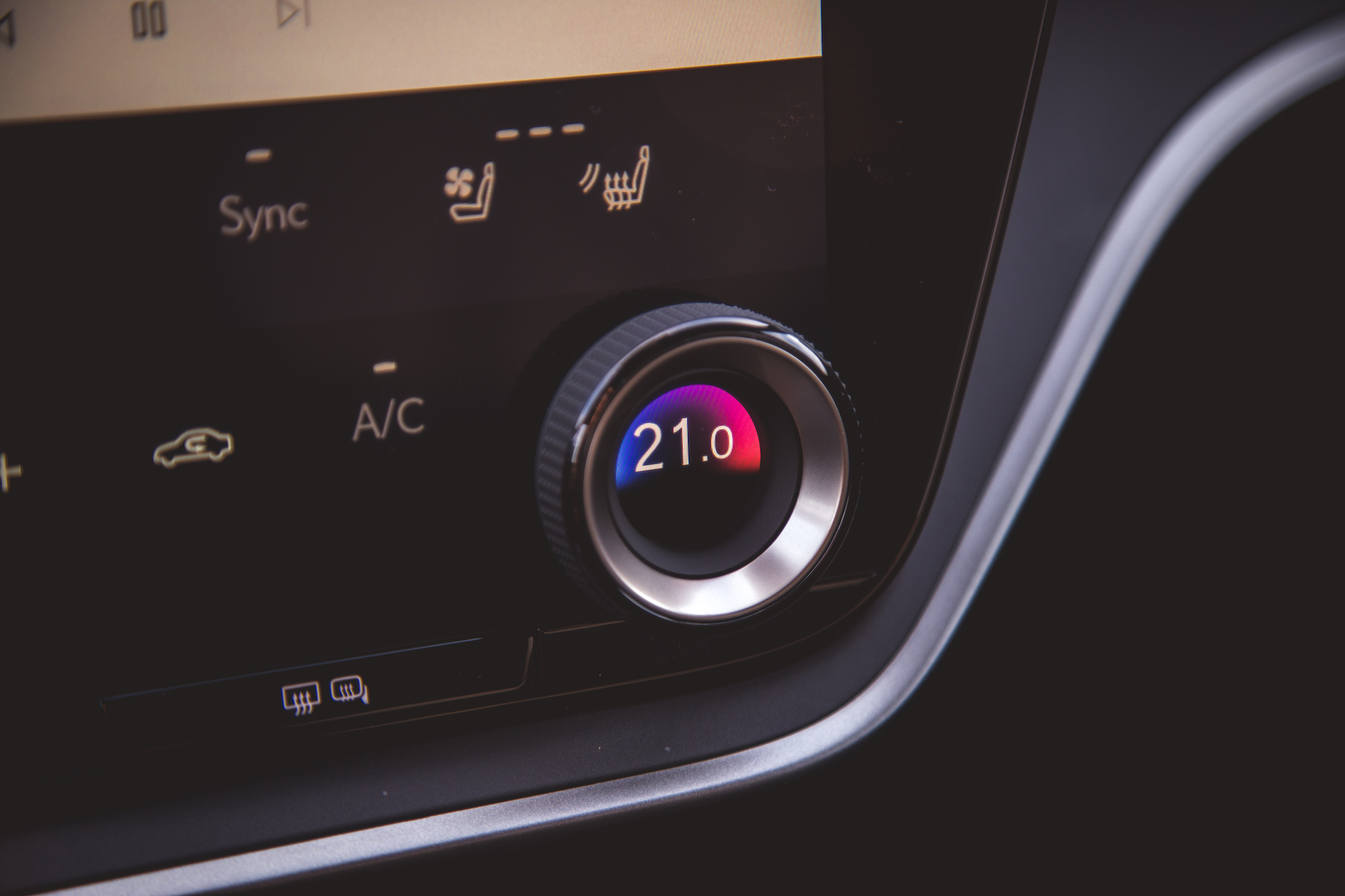 Close-up of a car climate control dial displaying a temperature setting of 21.0°C.