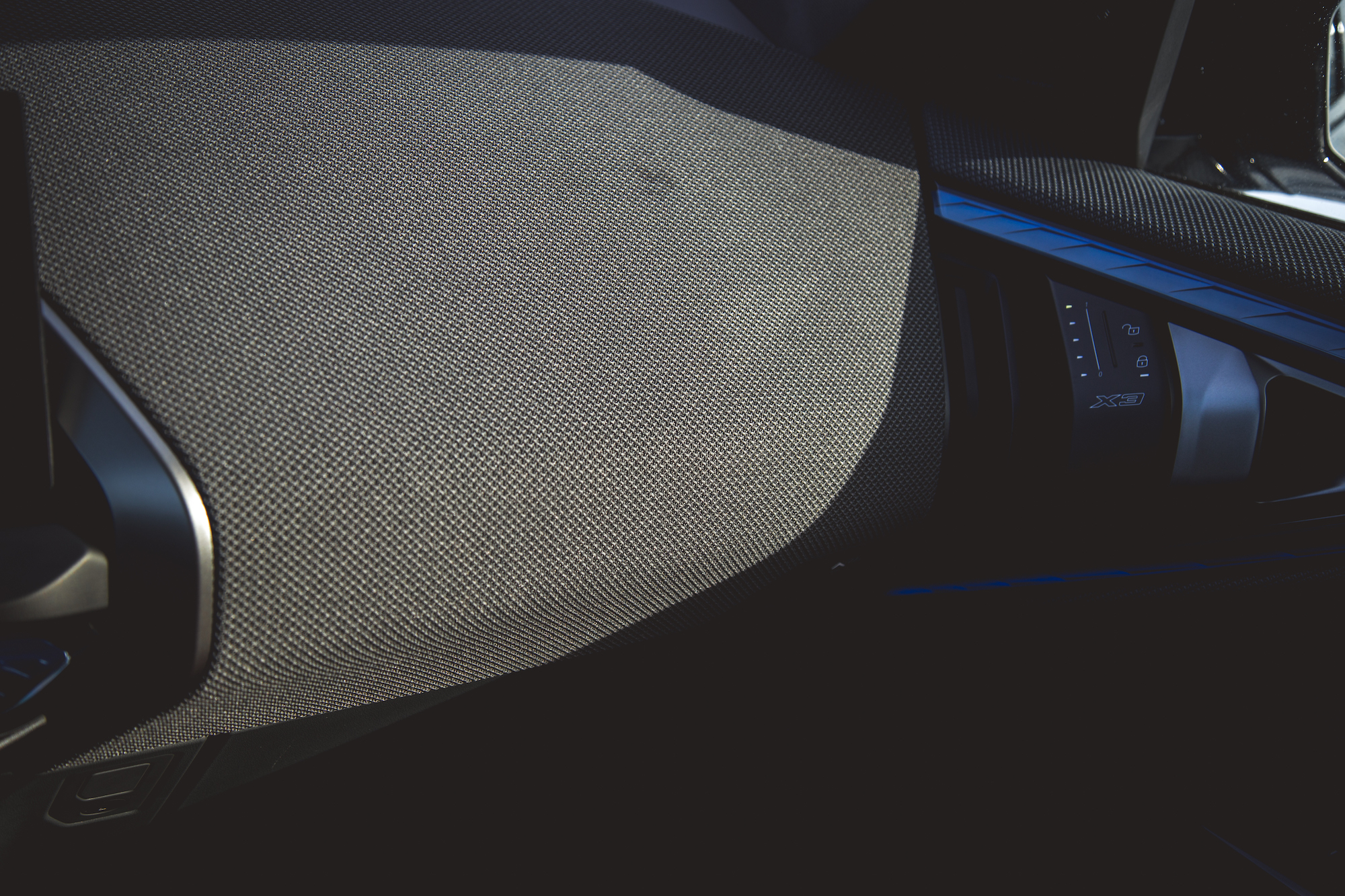 Close-up view of a textured car dashboard with a control panel and soft lighting.