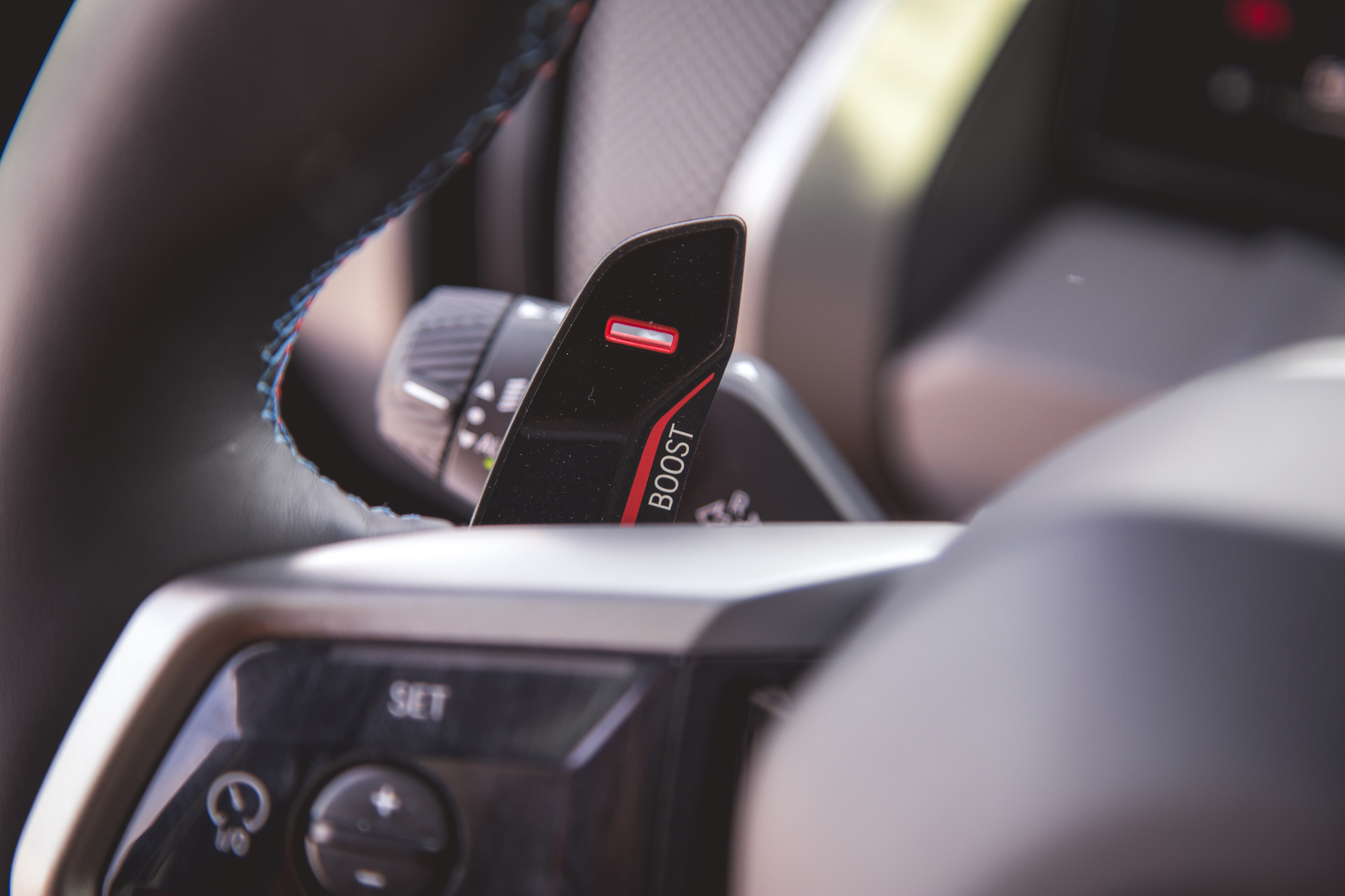 Close-up view of a car's steering wheel showing a 'BOOST' button and nearby controls.