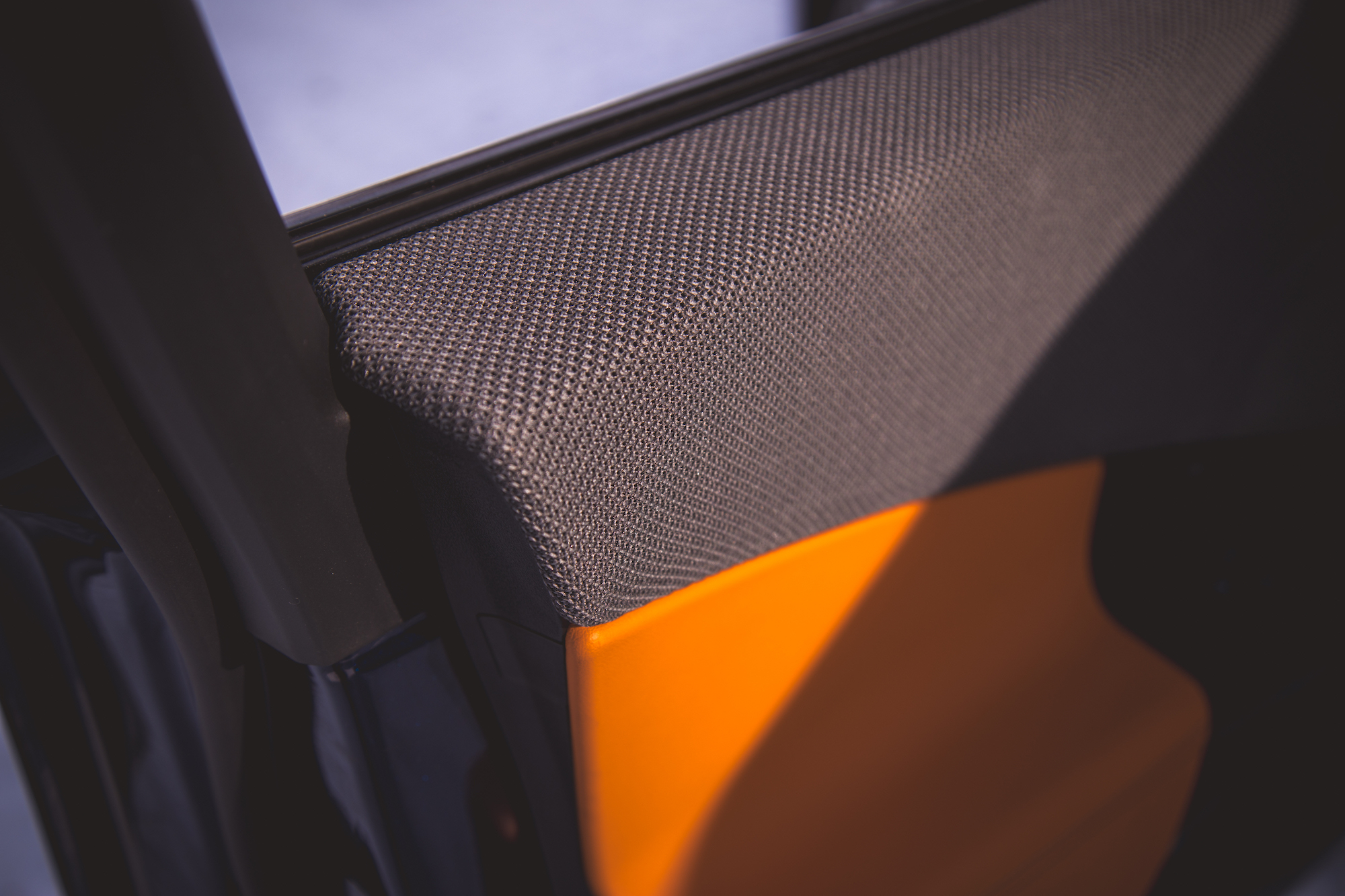 Close-up view of a car door interior, featuring textured fabric and a vibrant orange section.