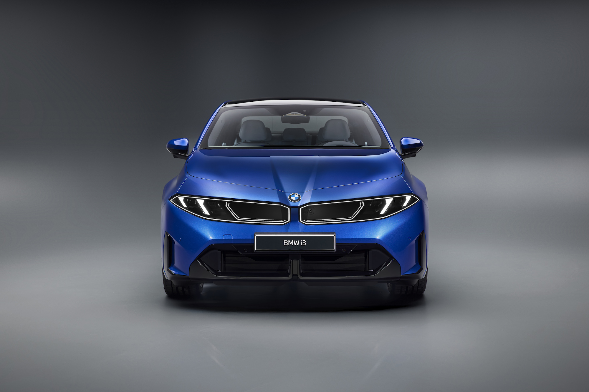 Front view of a blue BMW i3 electric car against a gray background.
