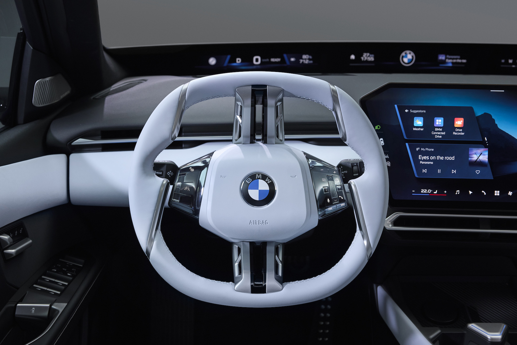 Close-up of a BMW vehicle's steering wheel featuring a modern design with controls and a digital display dashboard in the background.