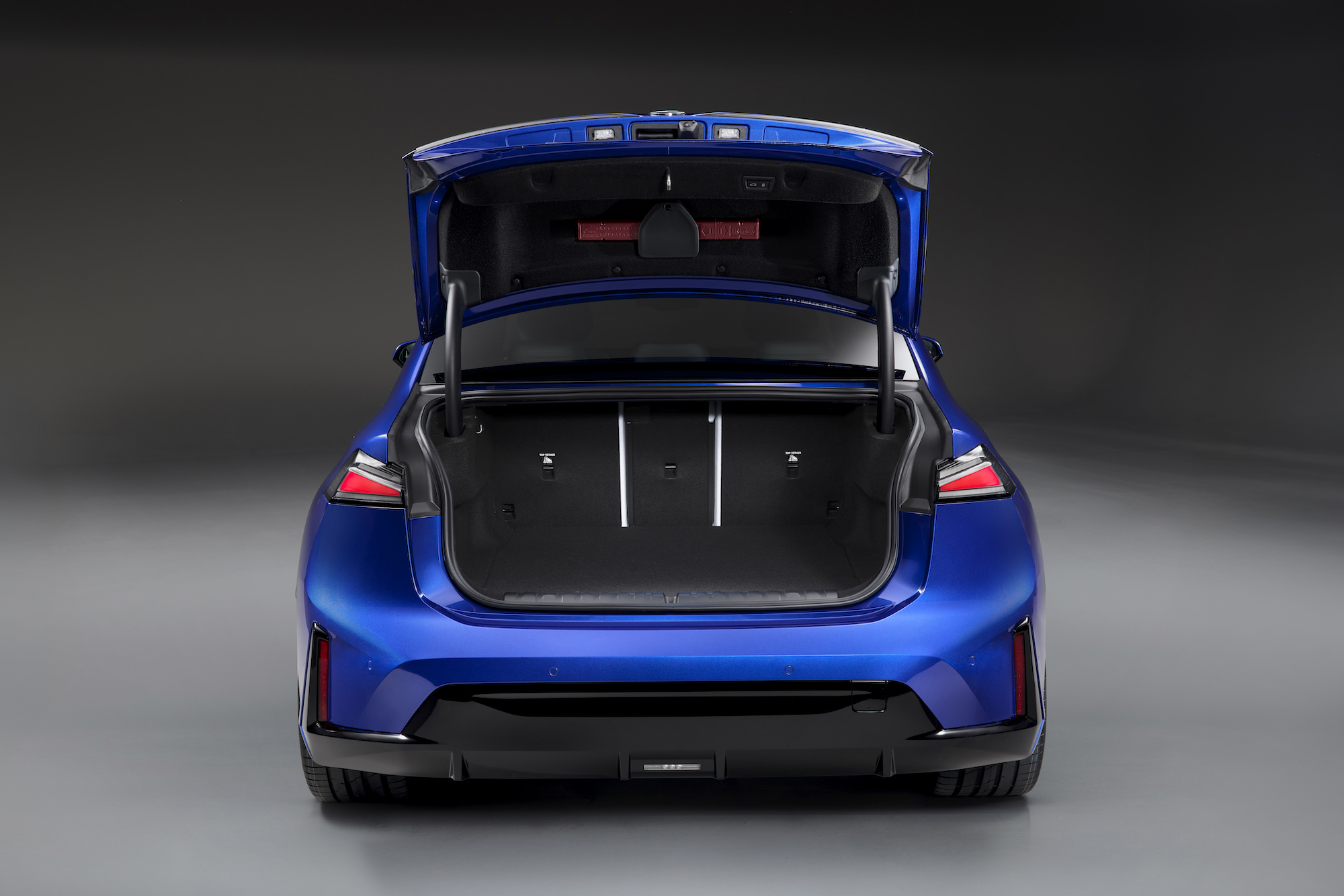 Rear view of a blue car with an open trunk, showcasing the spacious interior and sleek design.