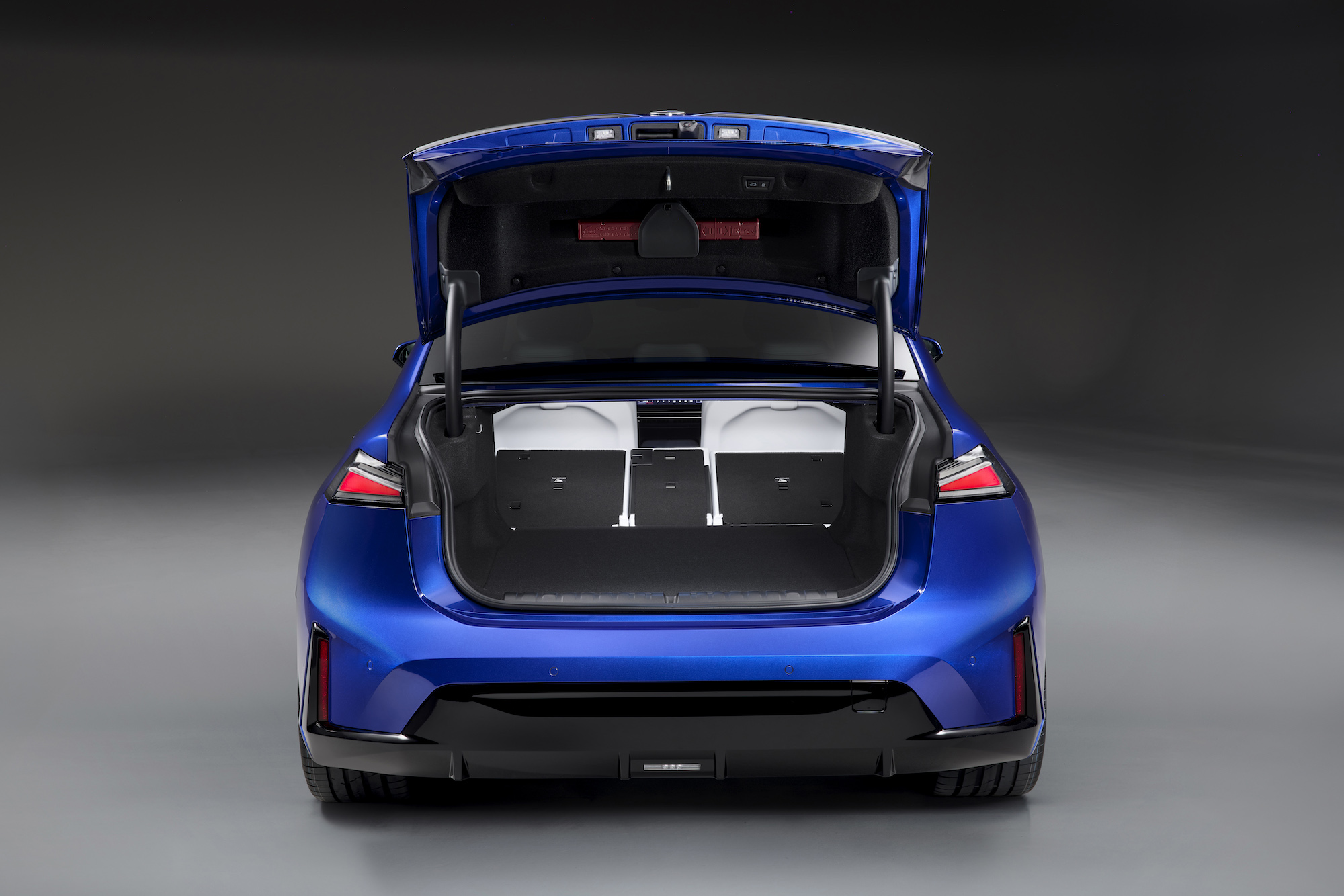 Rear view of a blue car with the trunk open, showcasing the spacious cargo area.