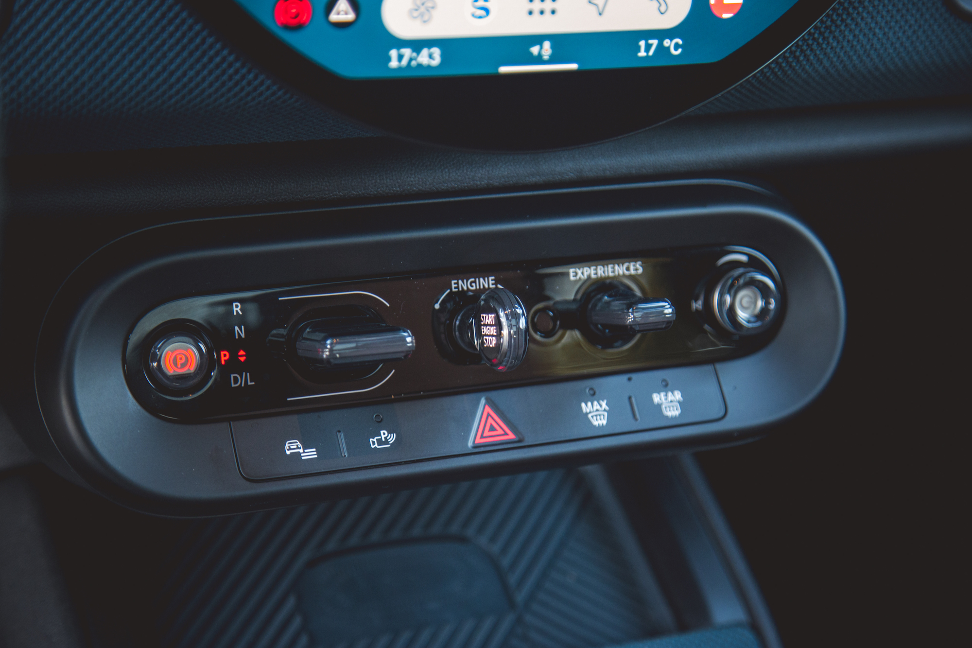 Close-up view of a car's control panel featuring gear shift options (P, R, N, D), engine start/stop button, and various function knobs.