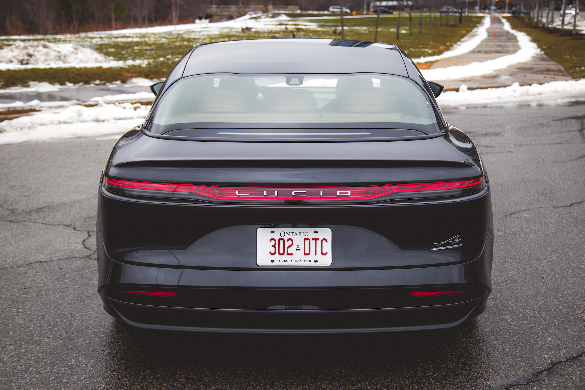 Vista trasera de un auto Lucid negro con un diseño elegante, que muestra sus distintivas luces traseras y su matrícula de Ontario.