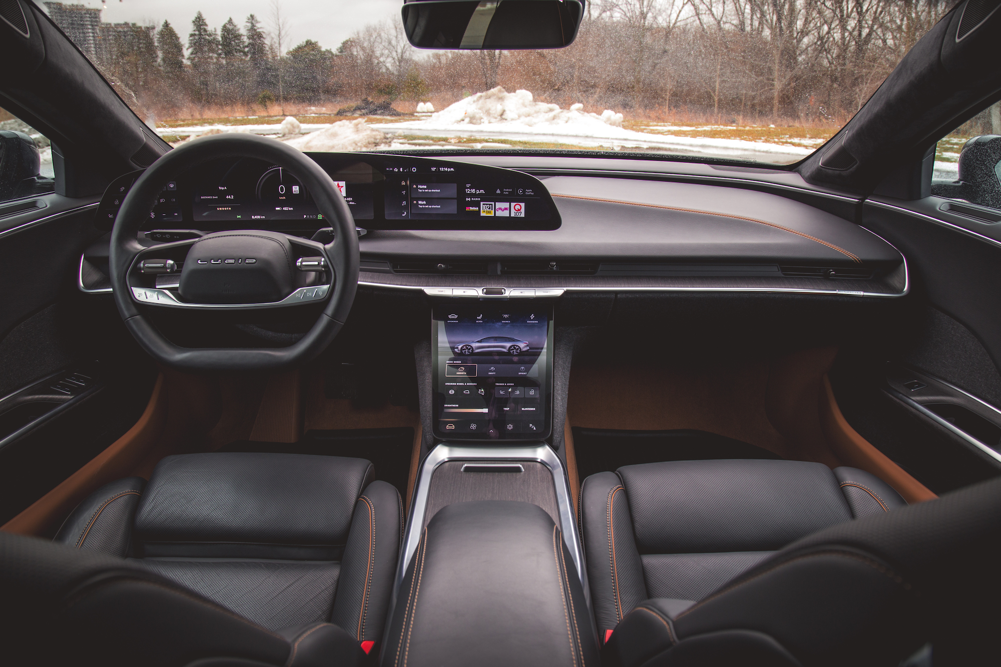 Vista interior de un automóvil de lujo con un tablero moderno, pantallas digitales y asientos de cuero.