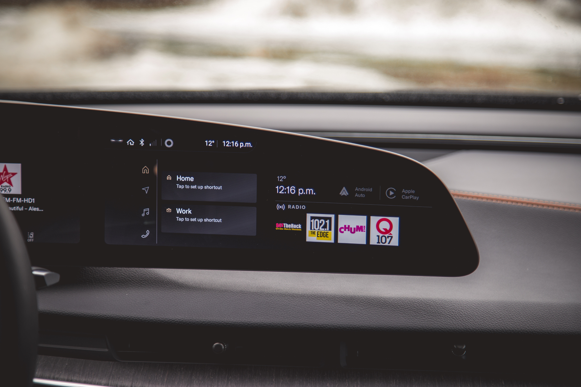 Primer plano del tablero de un automóvil con una pantalla digital con hora, temperatura y opciones de navegación para 