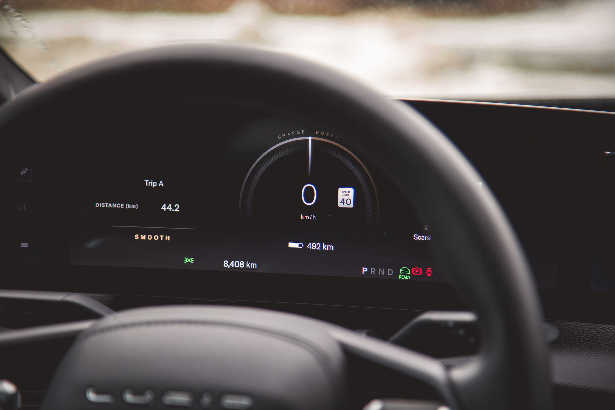 Vista de primer plano del tablero digital de un automóvil que muestra información del viaje, distancia recorrida, límite de velocidad, carga de la batería y lecturas del odómetro.