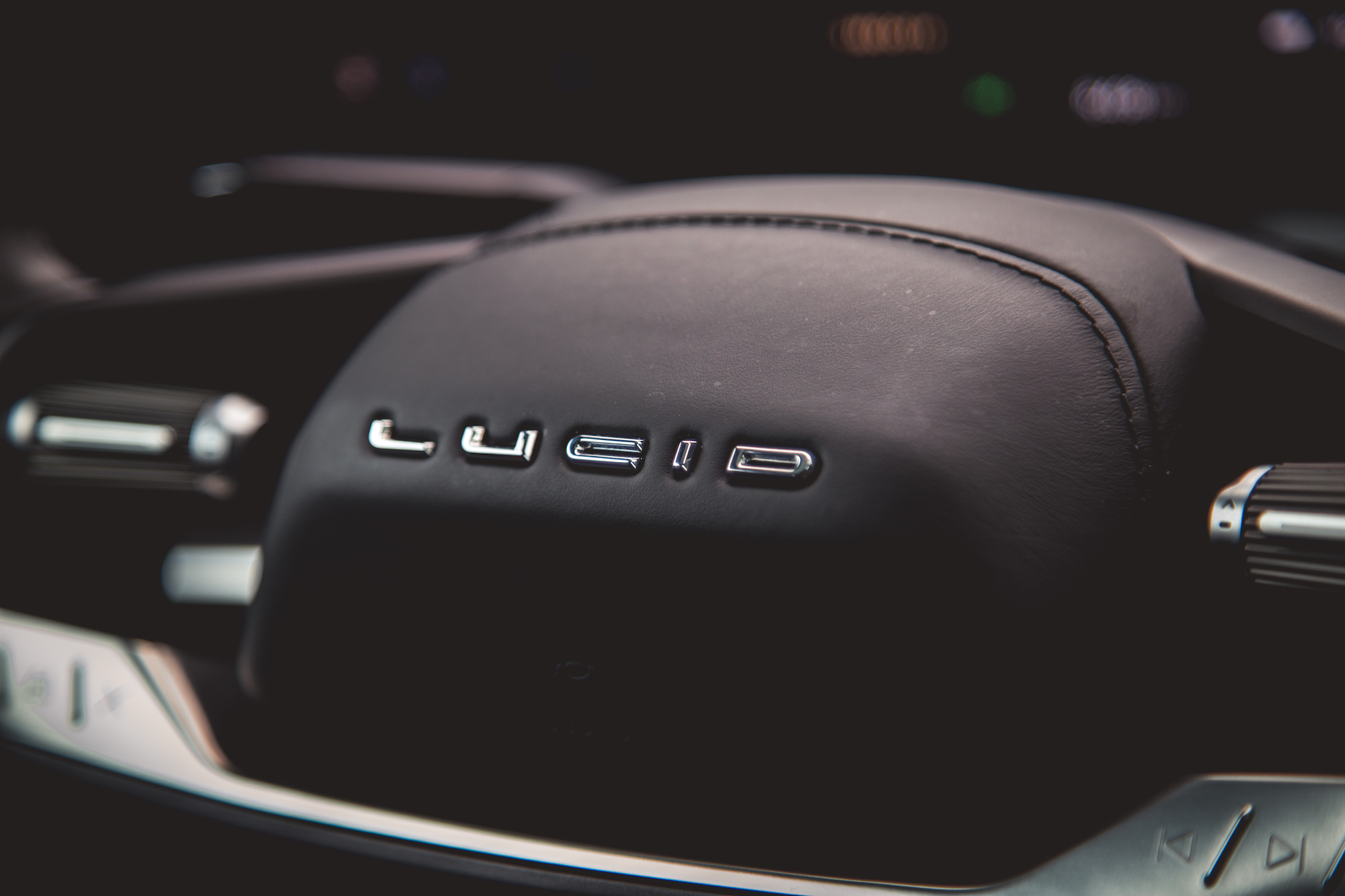 Primer plano del interior de un automóvil lujoso que muestra el logotipo de 'Lucid' en el tablero.