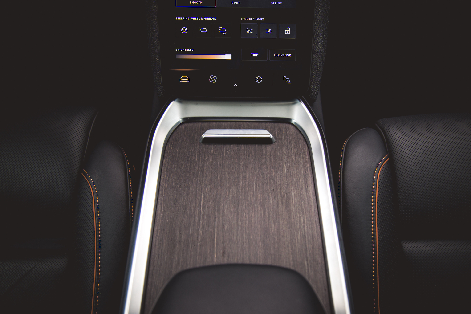 Primer plano de la consola central de un automóvil con un elegante acabado en madera, detalles metálicos y varios botones de control para configuraciones.