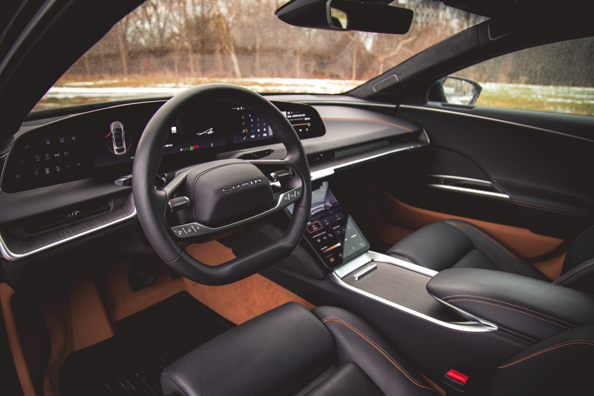 Vista interior de un automóvil eléctrico de lujo con un elegante tablero con pantalla digital, un volante moderno y cómodos asientos de cuero negro.