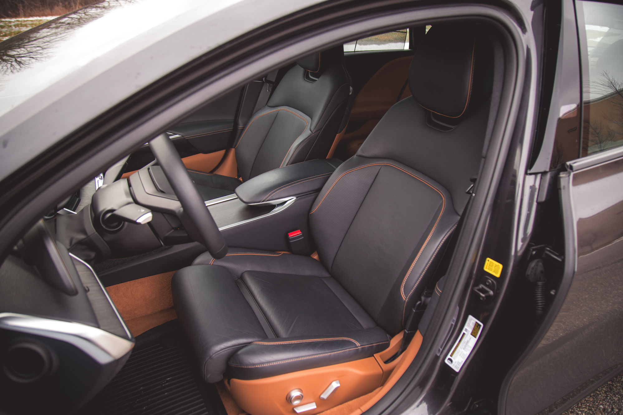 Vista interior de un automóvil que muestra asientos de cuero negro con costuras naranjas y un tablero de instrumentos de diseño moderno.