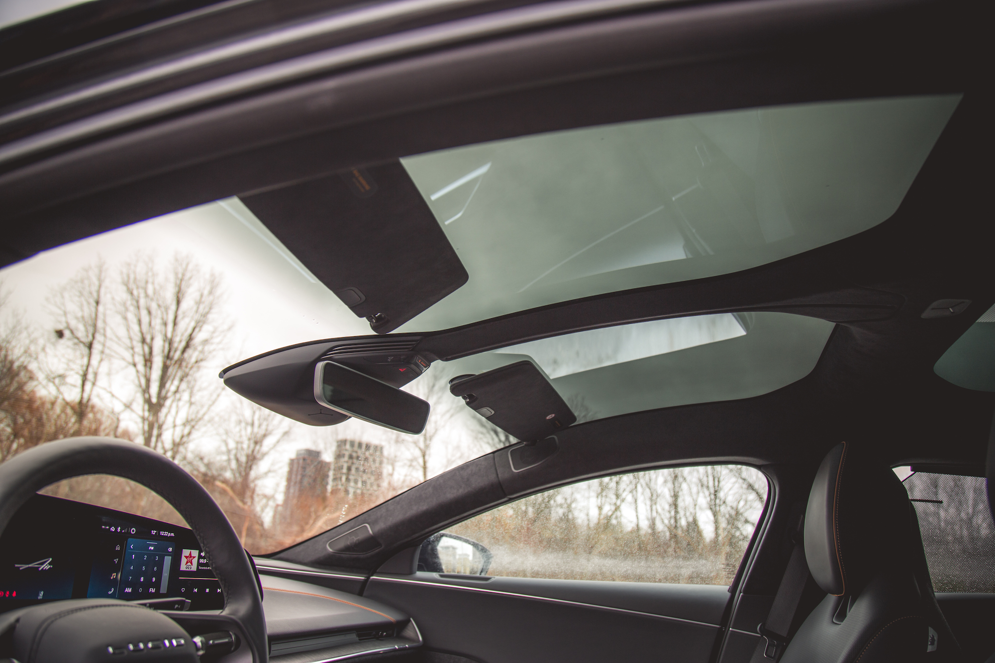 Vista interior de un automóvil que muestra un techo corredizo panorámico y un espejo retrovisor, con el tablero y el asiento del pasajero visibles.