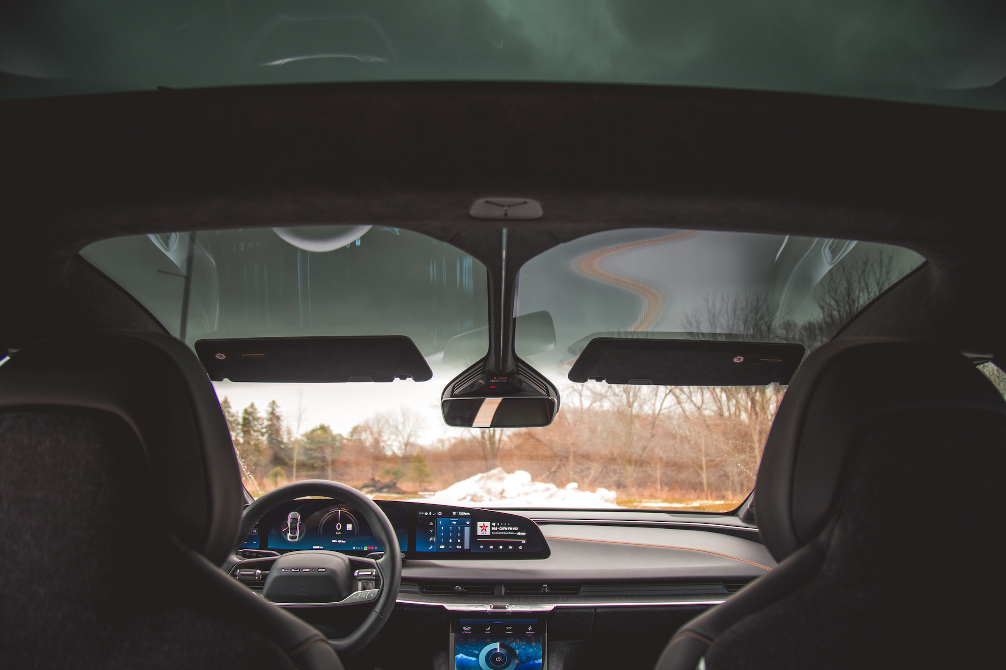 Vista interior de un automóvil moderno que muestra el volante, el tablero y el parabrisas grande con un fondo pintoresco al aire libre.