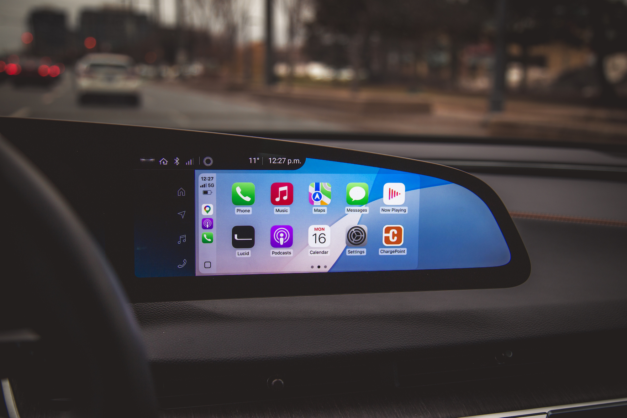 Primer plano de la pantalla de información y entretenimiento de un automóvil que presenta varios íconos de aplicaciones, como Teléfono, Música, Mapas y Mensajes, que muestran la hora y la temperatura.
