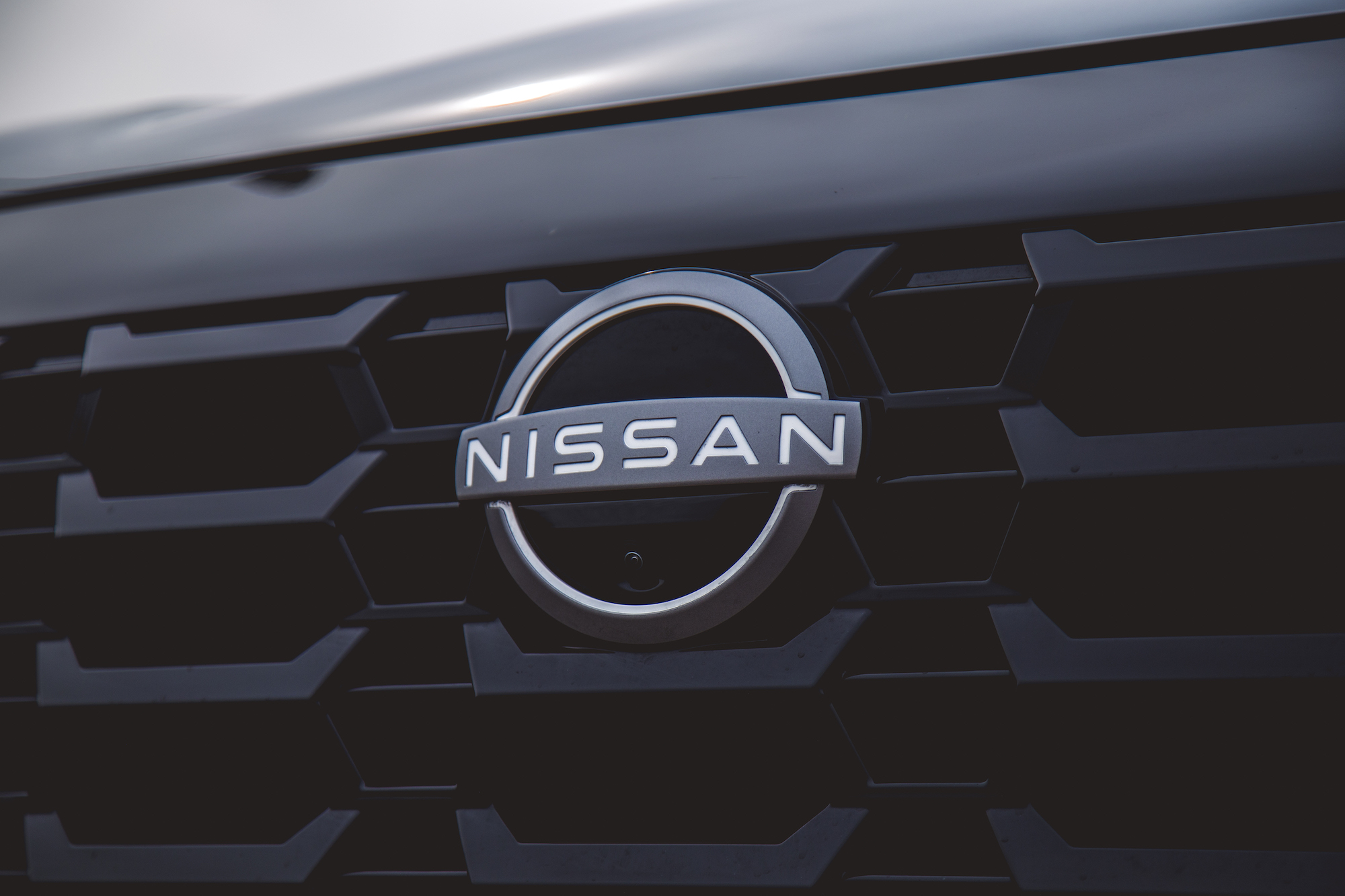Primer plano de un logotipo de Nissan en la parrilla de un automóvil negro