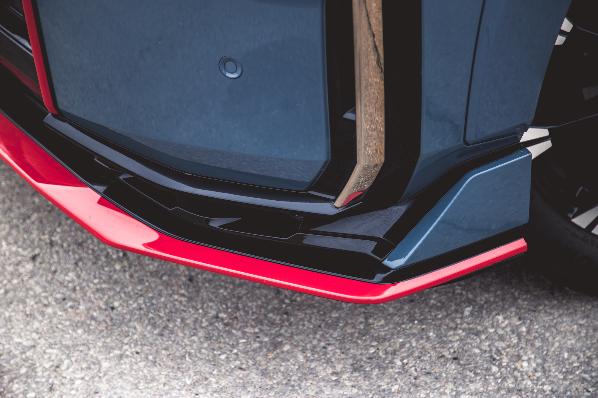 Primer plano de la sección inferior del parachoques delantero de un automóvil con un elegante diseño en negro y rojo.