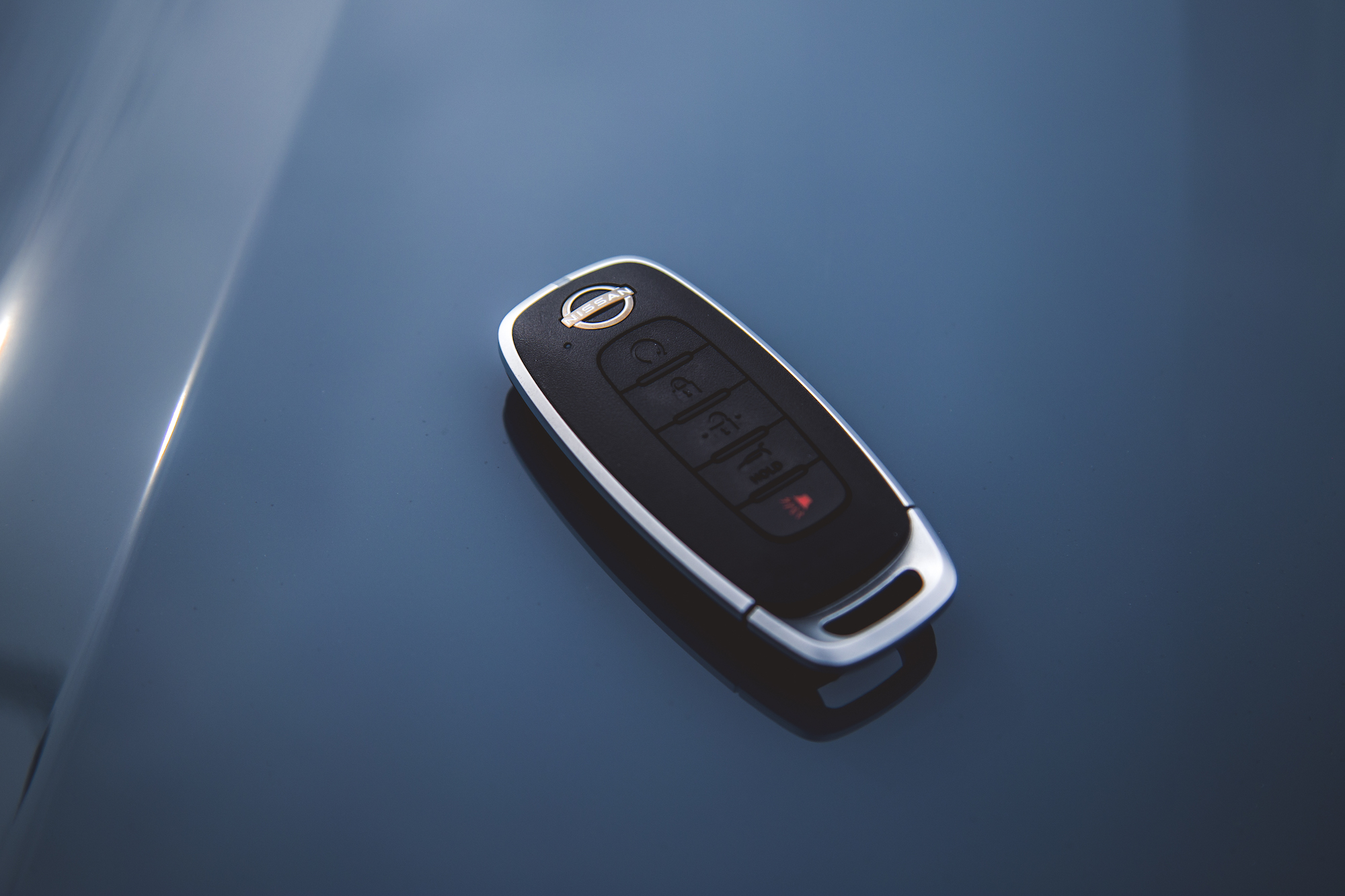 Un primer plano de un llavero de coche moderno apoyado sobre una superficie brillante.