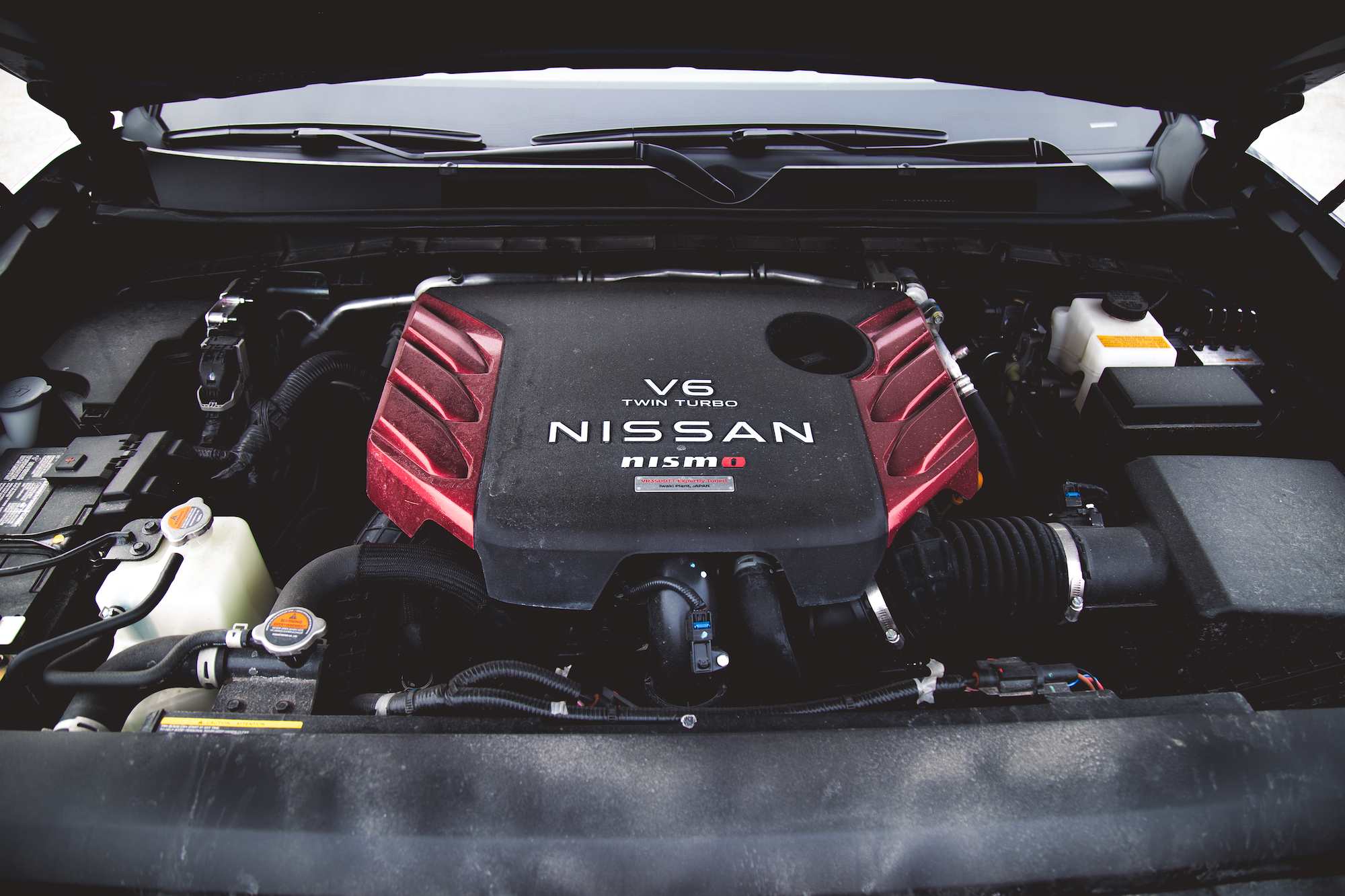 Vista cercana de un motor Nissan V6 biturbo con una cubierta de motor roja y negra.