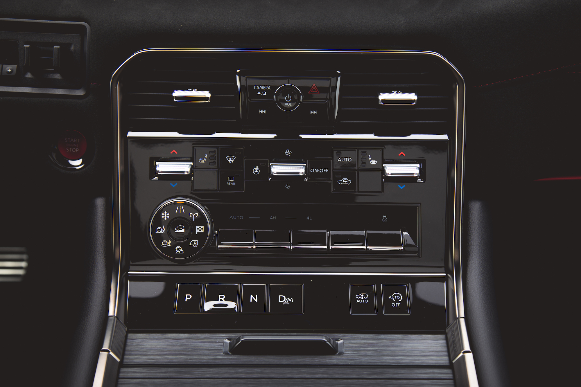 Primer plano del panel de control central de un automóvil con varios botones para control de clima, medios y modos de conducción.