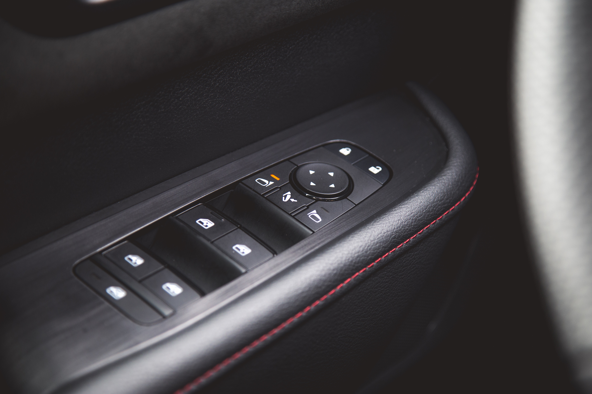 Primer plano del panel de control de la puerta de un automóvil con botones para bloquear, desbloquear y ajustar los espejos.