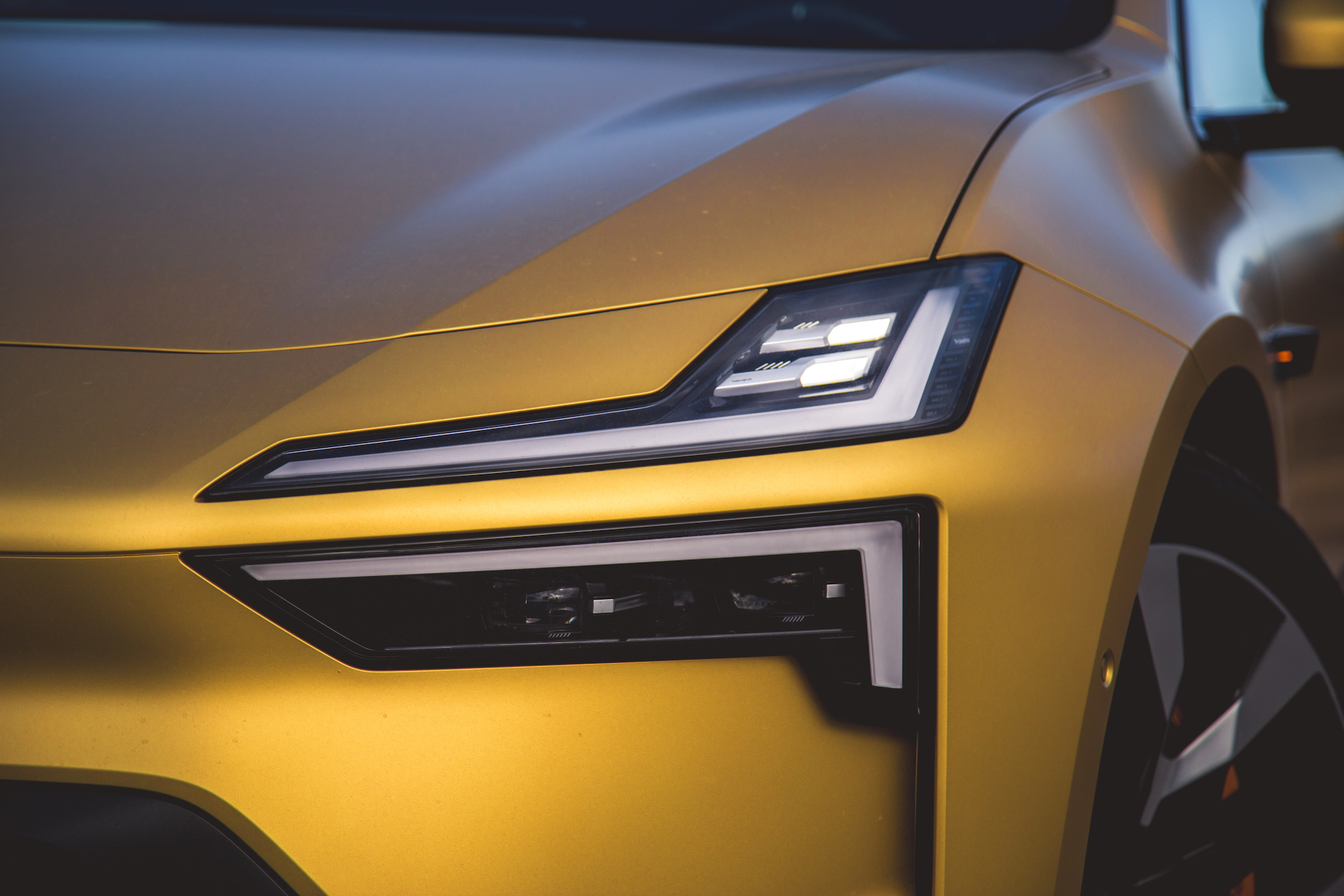 Primer plano del frente de un automóvil moderno con elegante pintura amarilla y faros distintivos.